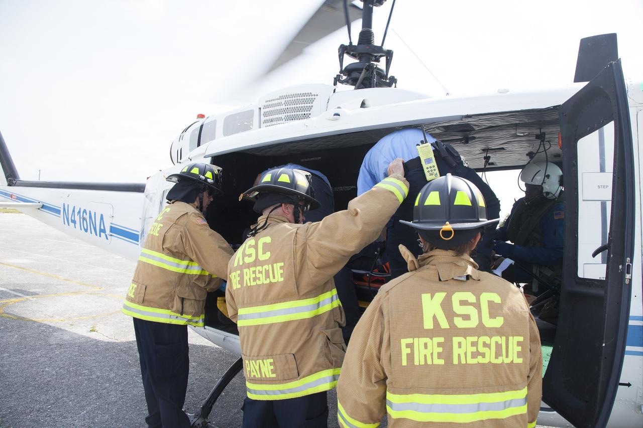 CAPE CANAVERAL, Fla. -- At NASA's Kennedy Space Center in Florida, a "volunteer patient" is carefully placed aboard a NASA helicopter as part of a training exercise. In an actual emergency, the pilots could fly an injured person from Kennedy to a nearby trauma center in minutes. The activity taking place in Kennedy's Launch Complex 39 turn-basin parking lot was only one of several drills. It was part of a new training program that was developed by Kennedy's Fire Rescue department along with NASA Aircraft Operations to sharpen the skills needed to help rescue personnel learn how to collaborate with helicopter pilots in taking injured patients to hospitals as quickly as possible. Photo credit: NASA/Dan Casper