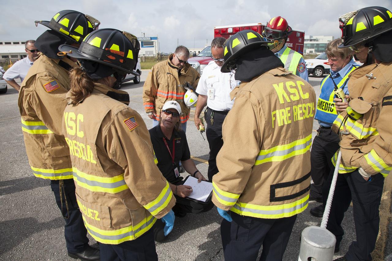 CAPE CANAVERAL, Fla. -- At NASA's Kennedy Space Center in Florida, Bill Martin, a URS Federal Technical Services helicopter pilot in NASA Aircraft Operations, kneeling, briefs NASA Fire Rescue personnel prior to the start of a simulated emergency.    The activity taking place in Kennedy's Launch Complex 39 turn-basin parking lot was only one of several drills. It was part of a new training program that was developed by Kennedy's Fire Rescue department along with NASA Aircraft Operations to sharpen the skills needed to help rescue personnel learn how to collaborate with helicopter pilots in taking injured patients to hospitals as quickly as possible. Photo credit: NASA/Dan Casper