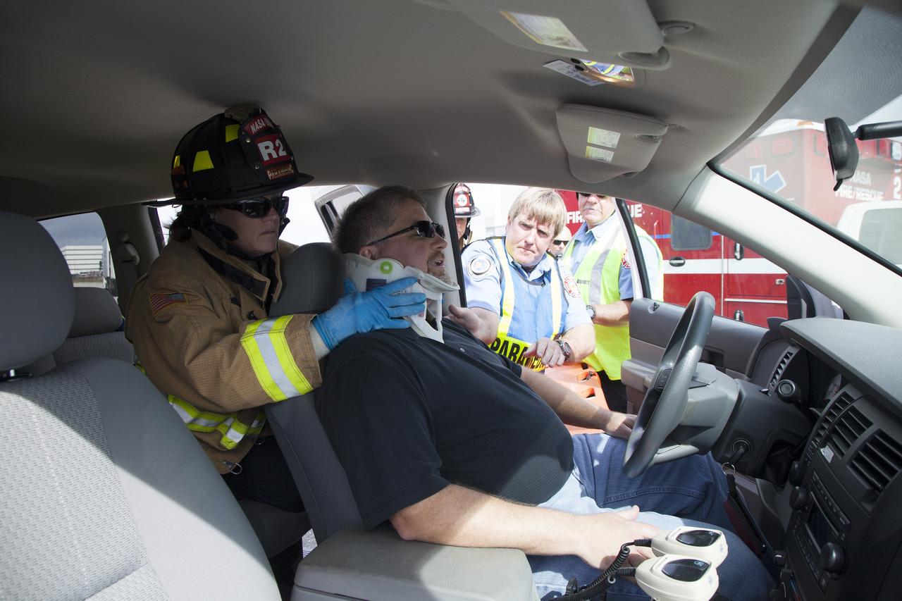CAPE CANAVERAL, Fla. -- At NASA's Kennedy Space Center in Florida, Lois Dominguez of Chenega Security & Support Solutions, who works in Fire Rescue operations, places a neck brace on George Jacobs, NASA deputy director NASA Center Operations, who is serving as a "volunteer patient." The activity taking place in Kennedy's Launch Complex 39 turn-basin parking lot was only one of several drills. It was part of a new training program that was developed by Kennedy's Fire Rescue department along with NASA Aircraft Operations to sharpen the skills needed to help rescue personnel learn how to collaborate with helicopter pilots in taking injured patients to hospitals as quickly as possible. Photo credit: NASA/Dan Casper
