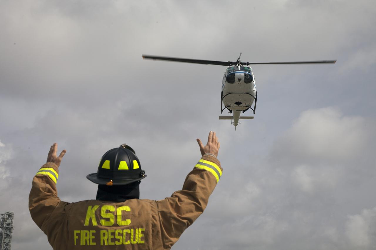 CAPE CANAVERAL, Fla. -- At NASA's Kennedy Space Center in Florida, NASA Fire Rescue Lt. David Tacy, of Chenega Security & Support Solutions, directs an agency helicopter in for a landing during a training exercise.    The activity taking place in Kennedy's Launch Complex 39 turn-basin parking lot was only one of several drills. It was part of a new training program that was developed by Kennedy's Fire Rescue department along with NASA Aircraft Operations to sharpen the skills needed to help rescue personnel learn how to collaborate with helicopter pilots in taking injured patients to hospitals as quickly as possible. Photo credit: NASA/Dan Casper