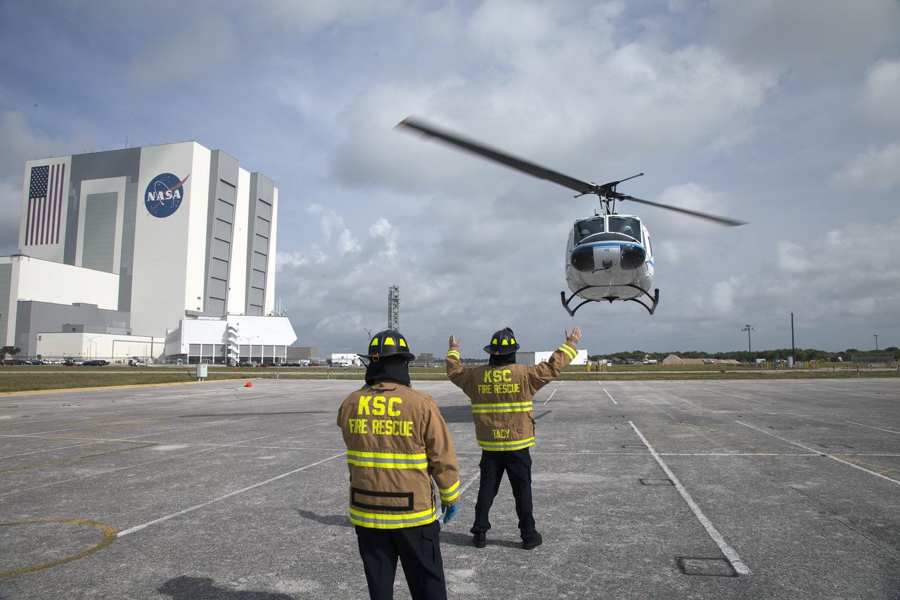CAPE CANAVERAL, Fla. -- At NASA's Kennedy Space Center in Florida, NASA Fire Rescue Lt. David Tacy, background, and firefighter Alvis Hickey direct an agency helicopter in for a landing for a training exercise. Tacy and Hickey both work for Chenega Security & Support Solutions and serve in Kennedy Fire Rescue Operations.    The activity taking place in Kennedy's Launch Complex 39 turn-basin parking lot was only one of several drills. It was part of a new training program that was developed by Kennedy's Fire Rescue department along with NASA Aircraft Operations to sharpen the skills needed to help rescue personnel learn how to collaborate with helicopter pilots in taking injured patients to hospitals as quickly as possible. Photo credit: NASA/Dan Casper