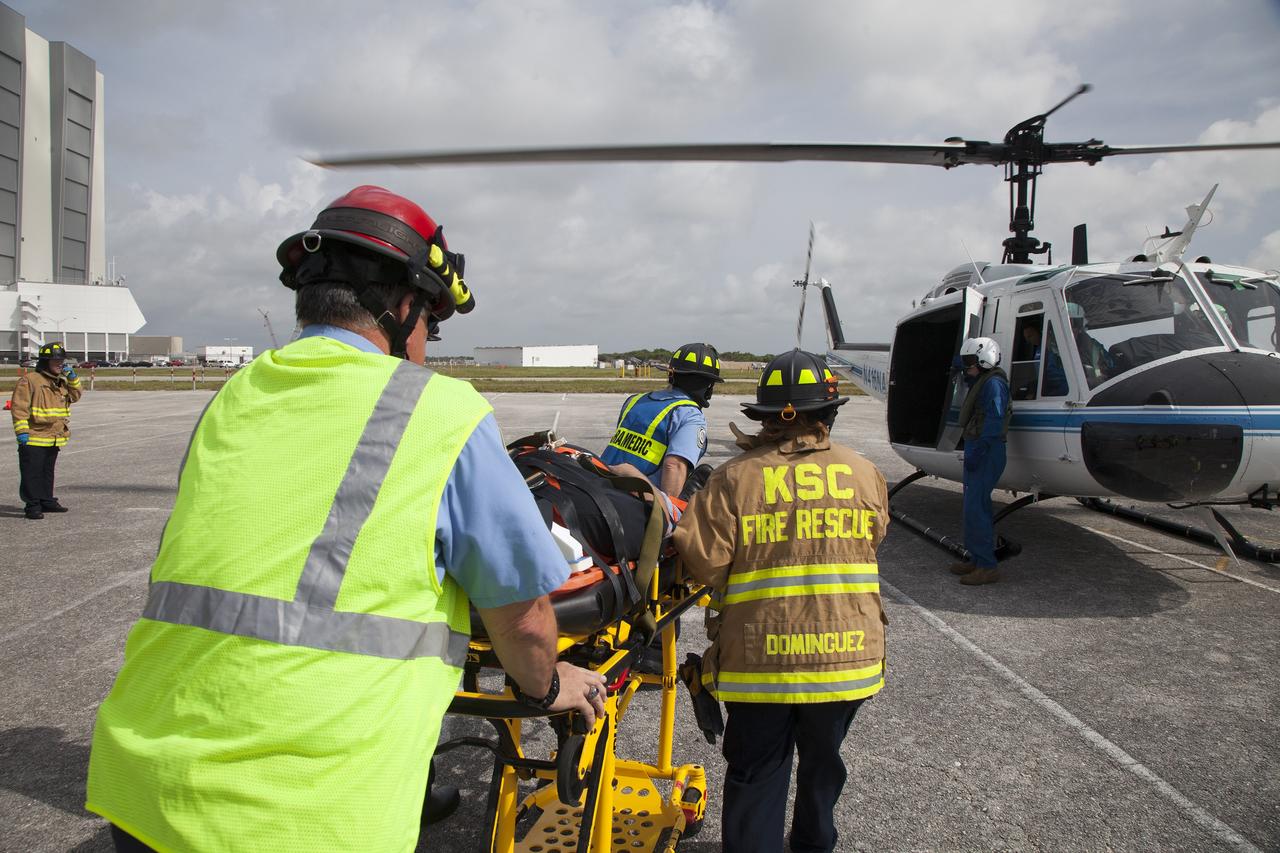 CAPE CANAVERAL, Fla. -- At NASA's Kennedy Space Center in Florida, Paramedics and Fire Rescue personnel move a stretcher to the waiting helicopter as they work quickly to have the patient ready to transport after he was removed from a vehicle.    The activity taking place in Kennedy's Launch Complex 39 turn-basin parking lot was only one of several drills. It was part of a new training program that was developed by Kennedy's Fire Rescue department along with NASA Aircraft Operations to sharpen the skills needed to help rescue personnel learn how to collaborate with helicopter pilots in taking injured patients to hospitals as quickly as possible. Photo credit: NASA/Dan Casper