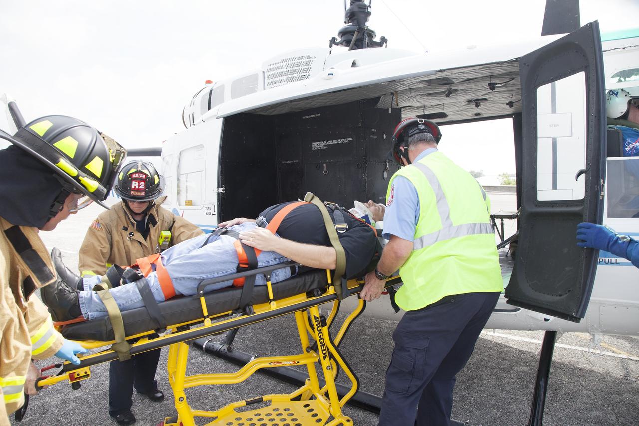 CAPE CANAVERAL, Fla. -- For a training exercise, "volunteer patient" George Jacobs, NASA's deputy director of Center Operations, is carefully placed aboard an agency helicopter at the Kennedy Space Center in Florida. In an actual emergency, the pilots could fly an injured person from Kennedy to a nearby trauma center in minutes. The activity taking place in Kennedy's Launch Complex 39 turn-basin parking lot was only one of several drills. It was part of a new training program that was developed by Kennedy's Fire Rescue department along with NASA Aircraft Operations to sharpen the skills needed to help rescue personnel learn how to collaborate with helicopter pilots in taking injured patients to hospitals as quickly as possible. Photo credit: NASA/Dan Casper