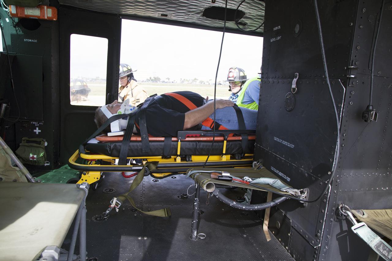 CAPE CANAVERAL, Fla. -- For a training exercise, "volunteer patient" George Jacobs, NASA's deputy director of Center Operations, has been carefully placed aboard an agency helicopter at the Kennedy Space Center in Florida. In an actual emergency, the pilots could fly an injured person from Kennedy to a nearby trauma center in minutes. The activity taking place in Kennedy's Launch Complex 39 turn-basin parking lot was only one of several drills. It was part of a new training program that was developed by Kennedy's Fire Rescue department along with NASA Aircraft Operations to sharpen the skills needed to help rescue personnel learn how to collaborate with helicopter pilots in taking injured patients to hospitals as quickly as possible. Photo credit: NASA/Dan Casper