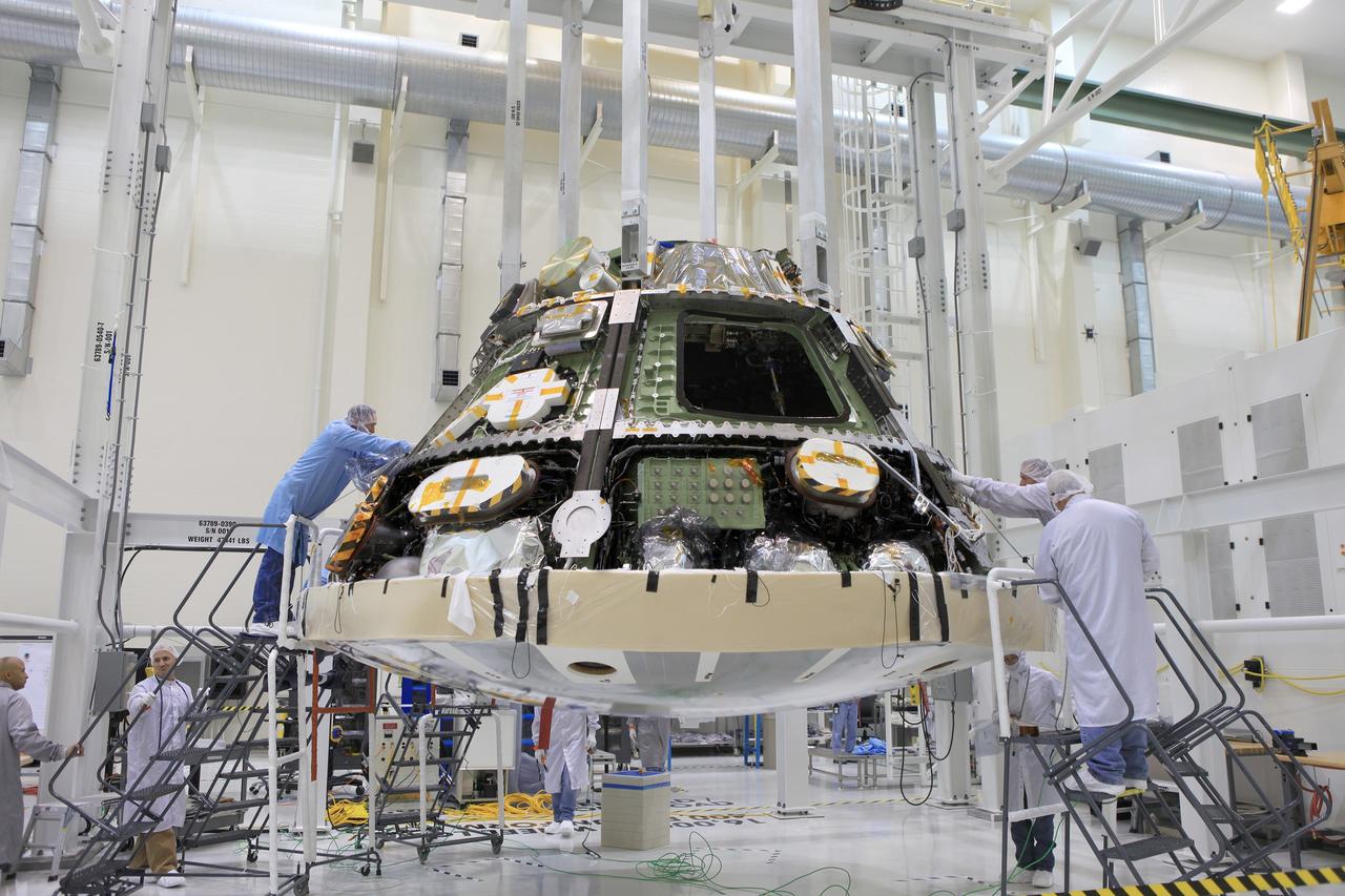 CAPE CANAVERAL, Fla. -- Lockheed Martin technicians and engineers attach the heat shield to the Orion crew module inside the Operations and Checkout Building high bay at NASA's Kennedy Space Center in Florida. Technicians have installed more than 200 instrumentation sensors on the heat shield for Exploration Flight Test-1, or EFT-1. The flight test will provide engineers with data about the heat shield's ability to protect Orion and its future crews from the 4,000-degree heat of reentry and an ocean splashdown following the spacecraft’s 20,000-mph reentry from space. Data gathered during the flight will inform decisions about design improvements on the heat shield and other Orion systems, and authenticate existing computer models and new approaches to space systems design and development. This process is critical to reducing overall risks and costs of future Orion missions.    Orion is the exploration spacecraft designed to carry astronauts to destinations not yet explored by humans, including an asteroid and Mars. It will have emergency abort capability, sustain the crew during space travel and provide safe re-entry from deep space return velocities. The first unpiloted test flight of the Orion is scheduled to launch later this year atop a Delta IV rocket from Cape Canaveral Air Force Station in Florida to an altitude of 3,600 miles above the Earth's surface. The two-orbit, four-hour flight test will help engineers evaluate the systems critical to crew safety including the heat shield, parachute system and launch abort system. For more information, visit http://www.nasa.gov/orion. Photo credit: NASA/Daniel Casper