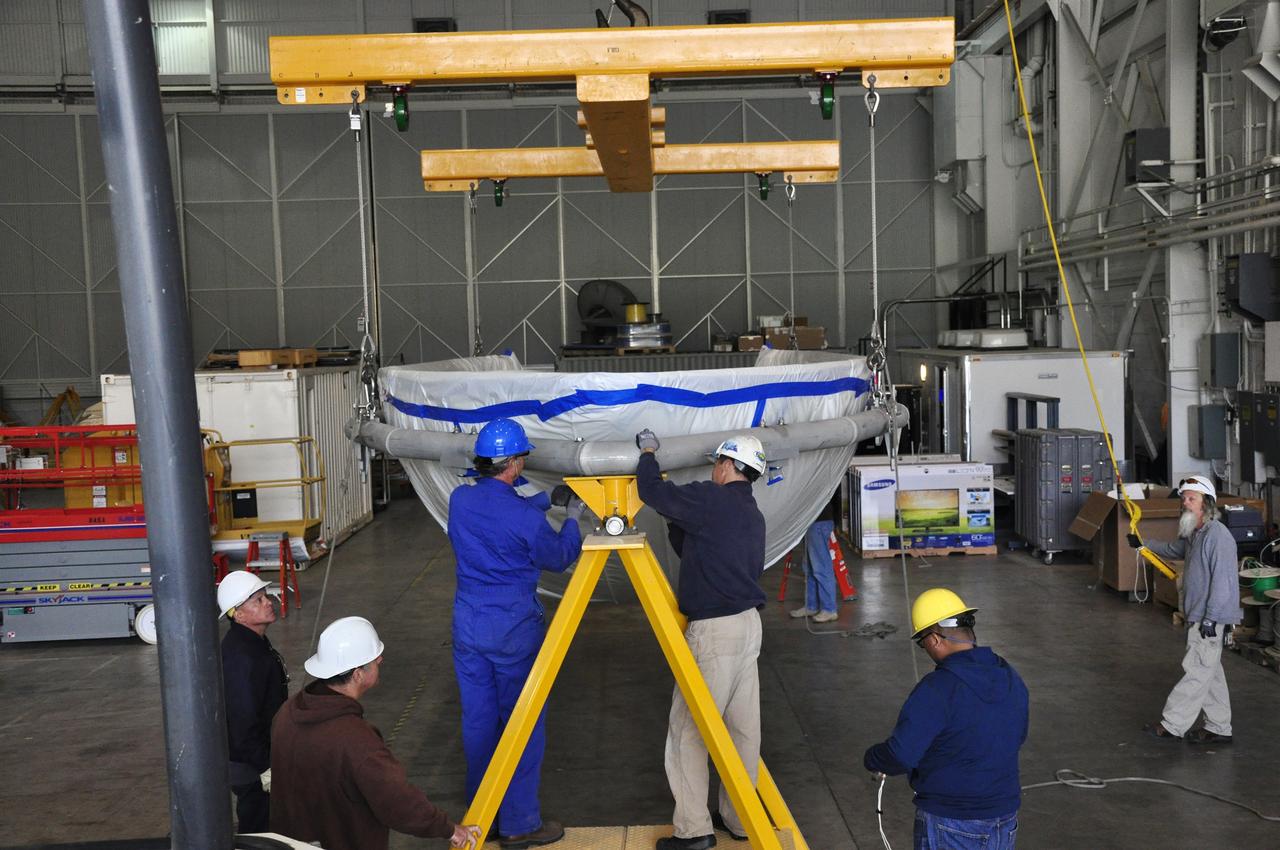 VANDENBERG AIR FORCE BASE, Calif. – Workers prepare to rotate a section of the fairing for NASA's Soil Moisture Active Passive mission, or SMAP, in a lifting device in the Building 836 high bay on Vandenberg Air Force Base in California. The fairing will protect the SMAP spacecraft from the heat and aerodynamic pressure generated during its ascent to orbit aboard a United Launch Alliance Delta II rocket from Space Launch Complex 2. SMAP will provide global measurements of soil moisture and its freeze/thaw state. These measurements will be used to enhance understanding of processes that link the water, energy and carbon cycles, and to extend the capabilities of weather and climate prediction models. SMAP data will also be used to quantify net carbon flux in boreal landscapes and to develop improved flood prediction and drought monitoring capabilities. Launch is scheduled for November 2014. To learn more about SMAP, visit http://smap.jpl.nasa.gov. Photo credit: NASA/Randy Beaudoin