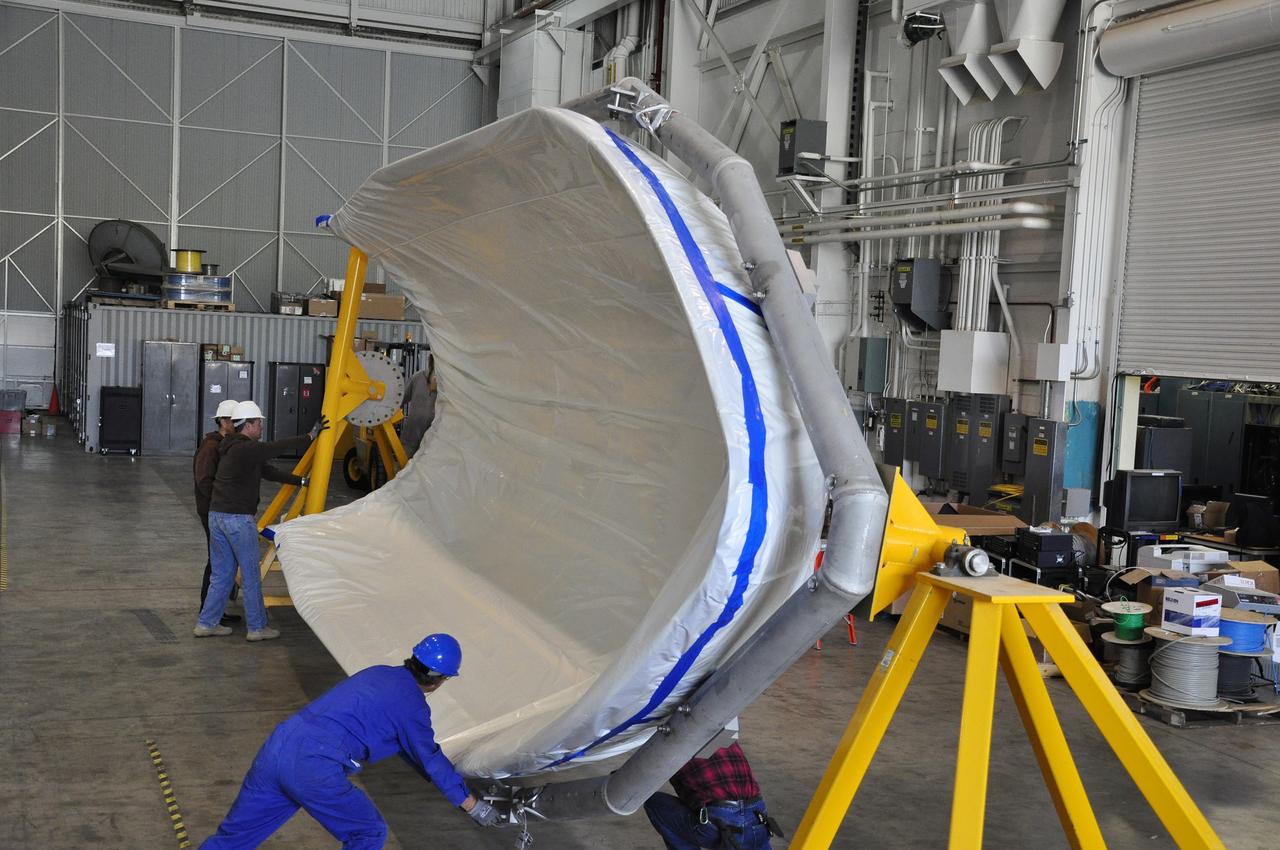 VANDENBERG AIR FORCE BASE, Calif. – Workers rotate a section of the fairing for NASA's Soil Moisture Active Passive mission, or SMAP, in a lifting device in the Building 836 high bay on Vandenberg Air Force Base in California. The fairing will protect the SMAP spacecraft from the heat and aerodynamic pressure generated during its ascent to orbit aboard a United Launch Alliance Delta II rocket from Space Launch Complex 2. SMAP will provide global measurements of soil moisture and its freeze/thaw state. These measurements will be used to enhance understanding of processes that link the water, energy and carbon cycles, and to extend the capabilities of weather and climate prediction models. SMAP data will also be used to quantify net carbon flux in boreal landscapes and to develop improved flood prediction and drought monitoring capabilities. Launch is scheduled for November 2014. To learn more about SMAP, visit http://smap.jpl.nasa.gov. Photo credit: NASA/Randy Beaudoin
