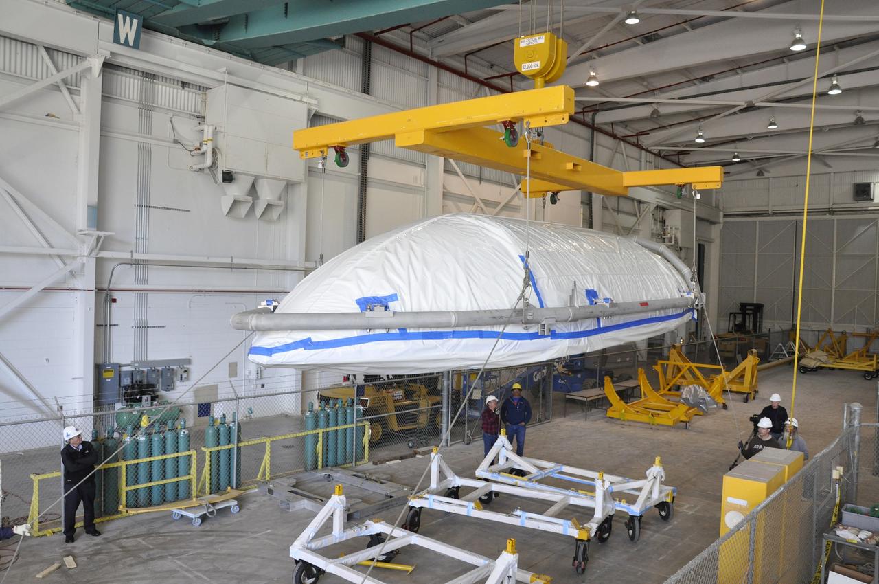 VANDENBERG AIR FORCE BASE, Calif. – Workers move a section of the fairing for NASA's Soil Moisture Active Passive mission, or SMAP, from a hardware dolly toward a transportation cradle in the Building 836 high bay on Vandenberg Air Force Base in California.    The fairing will protect the SMAP spacecraft from the heat and aerodynamic pressure generated during its ascent to orbit aboard a United Launch Alliance Delta II rocket from Space Launch Complex 2. SMAP will provide global measurements of soil moisture and its freeze/thaw state. These measurements will be used to enhance understanding of processes that link the water, energy and carbon cycles, and to extend the capabilities of weather and climate prediction models. SMAP data will also be used to quantify net carbon flux in boreal landscapes and to develop improved flood prediction and drought monitoring capabilities. Launch is scheduled for November 2014. To learn more about SMAP, visit http://smap.jpl.nasa.gov.  Photo credit: NASA/Randy Beaudoin