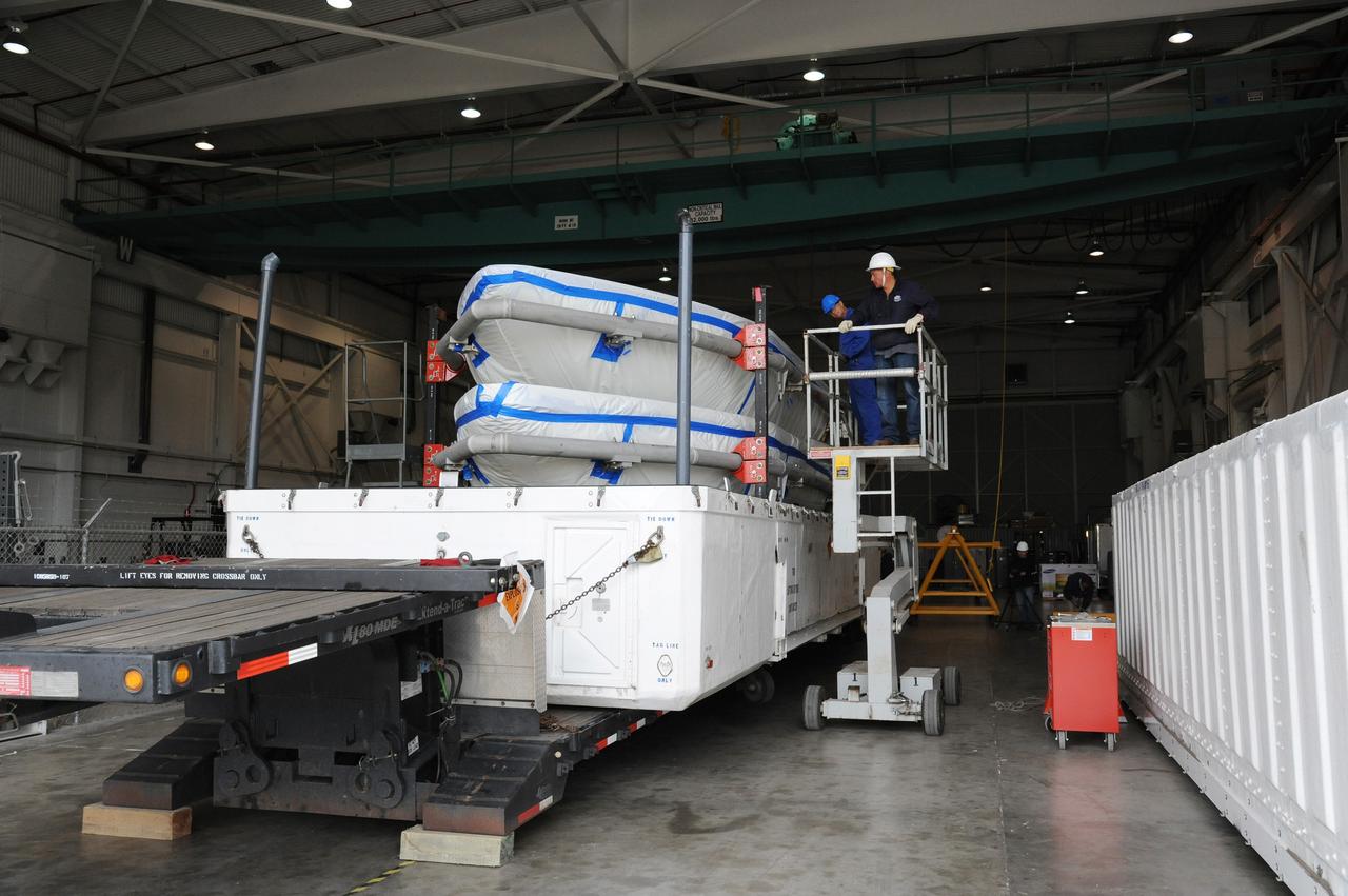 VANDENBERG AIR FORCE BASE, Calif. – Workers prepare to lift a half section of the 10-foot-diameter fairing for NASA's Soil Moisture Active Passive mission, or SMAP, from a transportation trailer in the Building 836 high bay on south Vandenberg Air Force Base in California.    The fairing will protect the SMAP spacecraft from the heat and aerodynamic pressure generated during its ascent to orbit aboard a United Launch Alliance Delta II rocket from Space Launch Complex 2. SMAP will provide global measurements of soil moisture and its freeze/thaw state. These measurements will be used to enhance understanding of processes that link the water, energy and carbon cycles, and to extend the capabilities of weather and climate prediction models. SMAP data will also be used to quantify net carbon flux in boreal landscapes and to develop improved flood prediction and drought monitoring capabilities. Launch is scheduled for November 2014. To learn more about SMAP, visit http://smap.jpl.nasa.gov.  Photo credit: NASA/U.S. Air Force 30th Space Wing