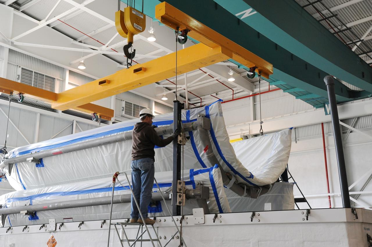 VANDENBERG AIR FORCE BASE, Calif. – Workers attach a half section of the 10-foot-diameter fairing for NASA's Soil Moisture Active Passive mission, or SMAP, to an overhead crane to lift it from a transportation trailer in the Building 836 high bay on south Vandenberg Air Force Base in California.    The fairing will protect the SMAP spacecraft from the heat and aerodynamic pressure generated during its ascent to orbit aboard a United Launch Alliance Delta II rocket from Space Launch Complex 2. SMAP will provide global measurements of soil moisture and its freeze/thaw state. These measurements will be used to enhance understanding of processes that link the water, energy and carbon cycles, and to extend the capabilities of weather and climate prediction models. SMAP data will also be used to quantify net carbon flux in boreal landscapes and to develop improved flood prediction and drought monitoring capabilities. Launch is scheduled for November 2014. To learn more about SMAP, visit http://smap.jpl.nasa.gov.  Photo credit: NASA/U.S. Air Force 30th Space Wing