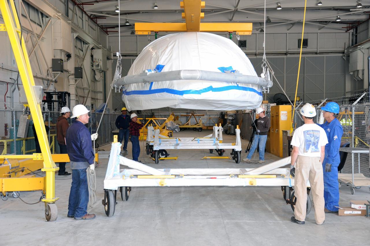 VANDENBERG AIR FORCE BASE, Calif. – Workers lower a half section of the 10-foot-diameter fairing for NASA's Soil Moisture Active Passive mission, or SMAP, onto a hardware dolly in the Building 836 high bay on south Vandenberg Air Force Base in California.    The fairing will protect the SMAP spacecraft from the heat and aerodynamic pressure generated during its ascent to orbit aboard a United Launch Alliance Delta II rocket from Space Launch Complex 2. SMAP will provide global measurements of soil moisture and its freeze/thaw state. These measurements will be used to enhance understanding of processes that link the water, energy and carbon cycles, and to extend the capabilities of weather and climate prediction models. SMAP data will also be used to quantify net carbon flux in boreal landscapes and to develop improved flood prediction and drought monitoring capabilities. Launch is scheduled for November 2014. To learn more about SMAP, visit http://smap.jpl.nasa.gov.  Photo credit: NASA/U.S. Air Force 30th Space Wing