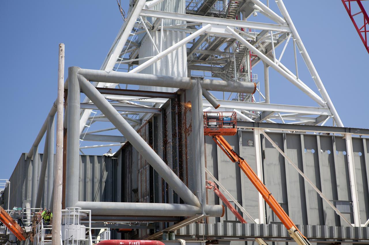 CAPE CANAVERAL, Fla. – Modifications continue on the Mobile Launcher, or ML, at the Mobile Launcher Park Site at NASA’s Kennedy Space Center in Florida. A construction worker on a lift continues to cut through a section of a steel beam to prepare it for removal. The ML is being modified and strengthened to accommodate the weight, size and thrust at launch of NASA's Space Launch System, or SLS, and Orion spacecraft.    In 2013, the agency awarded a contract to J.P. Donovan Construction Inc. of Rockledge, Fla., to modify the ML, which is one of the key elements of ground support equipment that is being upgraded by the Ground Systems Development and Operations Program office at Kennedy. The existing 24-foot exhaust hole is being enlarged and strengthened for the larger, heavier SLS rocket. The ML will carry the SLS rocket and Orion spacecraft to Launch Pad 39B for its first mission, Exploration Mission-1, in 2017. Photo credit: NASA/Dimitri Gerondidakis