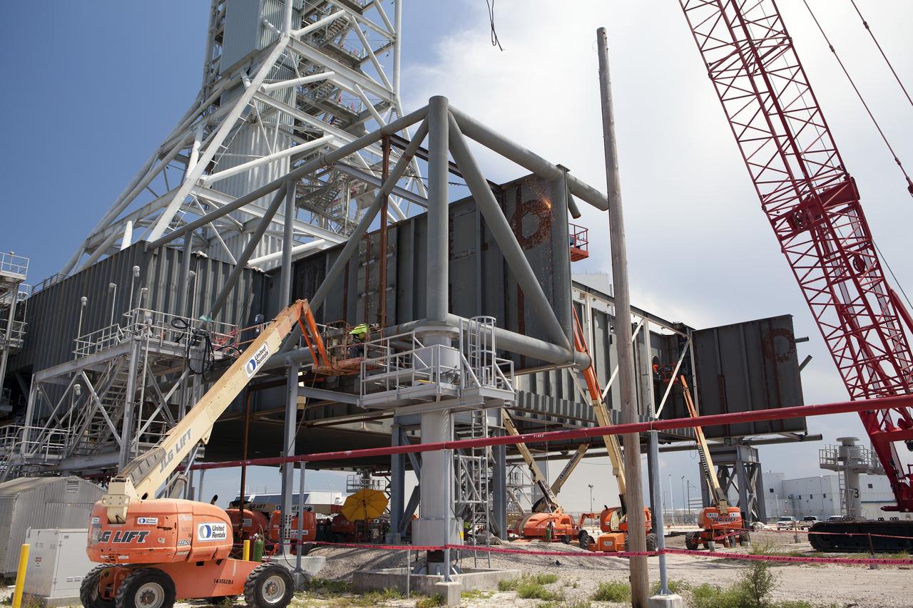 CAPE CANAVERAL, Fla. – Modifications continue on the Mobile Launcher, or ML, at the Mobile Launcher Park Site at NASA’s Kennedy Space Center in Florida. Construction workers on lifts continue to cut through a steel beam to prepare it for removal. The ML is being modified and strengthened to accommodate the weight, size and thrust at launch of NASA's Space Launch System, or SLS, and Orion spacecraft.    In 2013, the agency awarded a contract to J.P. Donovan Construction Inc. of Rockledge, Fla., to modify the ML, which is one of the key elements of ground support equipment that is being upgraded by the Ground Systems Development and Operations Program office at Kennedy. The existing 24-foot exhaust hole is being enlarged and strengthened for the larger, heavier SLS rocket. The ML will carry the SLS rocket and Orion spacecraft to Launch Pad 39B for its first mission, Exploration Mission-1, in 2017. Photo credit: NASA/Dimitri Gerondidakis