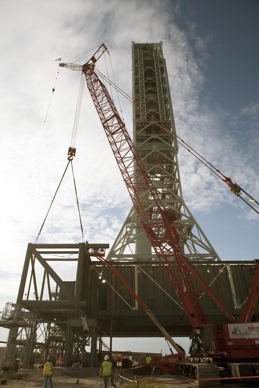CAPE CANAVERAL, Fla. – Modifications continue on the Mobile Launcher, or ML, at the Mobile Launcher Park Site at NASA’s Kennedy Space Center in Florida. A crane is used to lift a section of the metal structure away from the ML. The ML is being modified and strengthened to accommodate the weight, size and thrust at launch of NASA's Space Launch System, or SLS, and Orion spacecraft.    In 2013, the agency awarded a contract to J.P. Donovan Construction Inc. of Rockledge, Fla., to modify the ML, which is one of the key elements of ground support equipment that is being upgraded by the Ground Systems Development and Operations Program office at Kennedy. The existing 24-foot exhaust hole is being enlarged and strengthened for the larger, heavier SLS rocket. The ML will carry the SLS rocket and Orion spacecraft to Launch Pad 39B for its first mission, Exploration Mission-1, in 2017. Photo credit: NASA/Daniel Casper