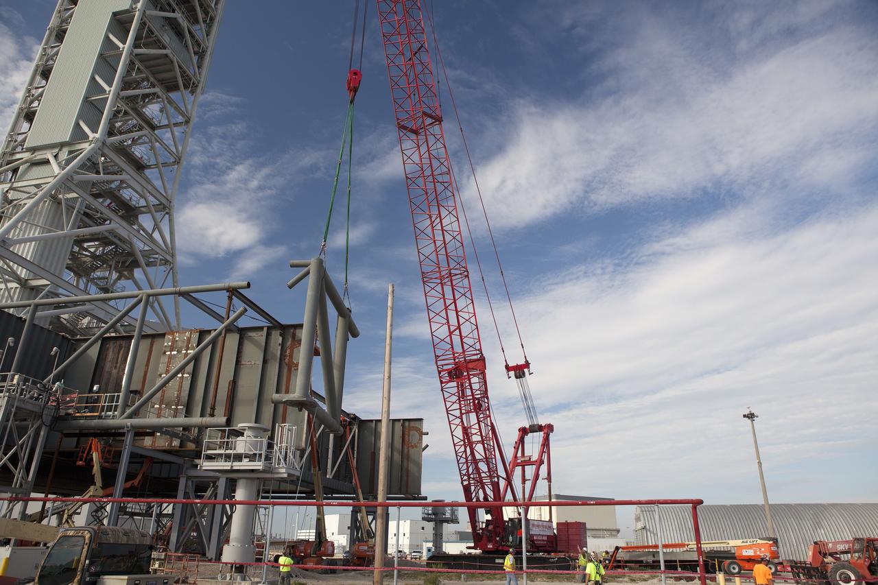 CAPE CANAVERAL, Fla. – Modifications continue on the Mobile Launcher, or ML, at the Mobile Launcher Park Site at NASA’s Kennedy Space Center in Florida. A crane is used to lift a section of the metal structure away from the ML. The ML is being modified and strengthened to accommodate the weight, size and thrust at launch of NASA's Space Launch System, or SLS, and Orion spacecraft.    In 2013, the agency awarded a contract to J.P. Donovan Construction Inc. of Rockledge, Fla., to modify the ML, which is one of the key elements of ground support equipment that is being upgraded by the Ground Systems Development and Operations Program office at Kennedy. The existing 24-foot exhaust hole is being enlarged and strengthened for the larger, heavier SLS rocket. The ML will carry the SLS rocket and Orion spacecraft to Launch Pad 39B for its first mission, Exploration Mission-1, in 2017. Photo credit: NASA/Daniel Casper