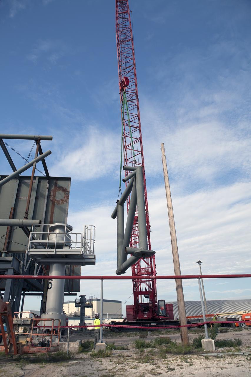 CAPE CANAVERAL, Fla. – Modifications continue on the Mobile Launcher, or ML, at the Mobile Launcher Park Site at NASA’s Kennedy Space Center in Florida. A section of the metal structure is lifted away from the ML. The ML is being modified and strengthened to accommodate the weight, size and thrust at launch of NASA's Space Launch System, or SLS, and Orion spacecraft.    In 2013, the agency awarded a contract to J.P. Donovan Construction Inc. of Rockledge, Fla., to modify the ML, which is one of the key elements of ground support equipment that is being upgraded by the Ground Systems Development and Operations Program office at Kennedy. The existing 24-foot exhaust hole is being enlarged and strengthened for the larger, heavier SLS rocket. The ML will carry the SLS rocket and Orion spacecraft to Launch Pad 39B for its first mission, Exploration Mission-1, in 2017. Photo credit: NASA/Daniel Casper