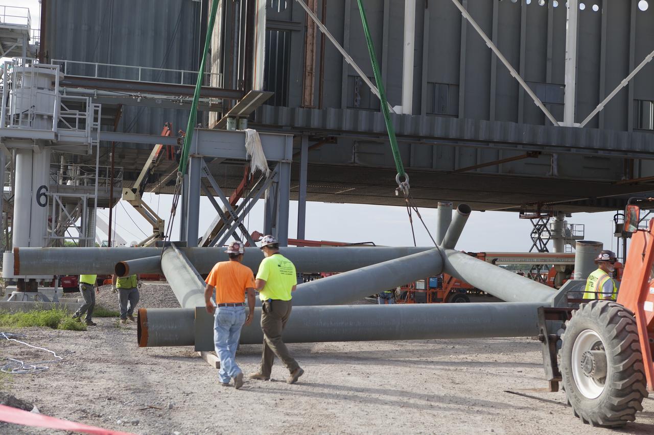 CAPE CANAVERAL, Fla. – Modifications continue on the Mobile Launcher, or ML, at the Mobile Launcher Park Site at NASA’s Kennedy Space Center in Florida. A section of the metal structure is lowered by crane to the ground near the ML. The ML is being modified and strengthened to accommodate the weight, size and thrust at launch of NASA's Space Launch System, or SLS, and Orion spacecraft.    In 2013, the agency awarded a contract to J.P. Donovan Construction Inc. of Rockledge, Fla., to modify the ML, which is one of the key elements of ground support equipment that is being upgraded by the Ground Systems Development and Operations Program office at Kennedy. The existing 24-foot exhaust hole is being enlarged and strengthened for the larger, heavier SLS rocket. The ML will carry the SLS rocket and Orion spacecraft to Launch Pad 39B for its first mission, Exploration Mission-1, in 2017. Photo credit: NASA/Daniel Casper