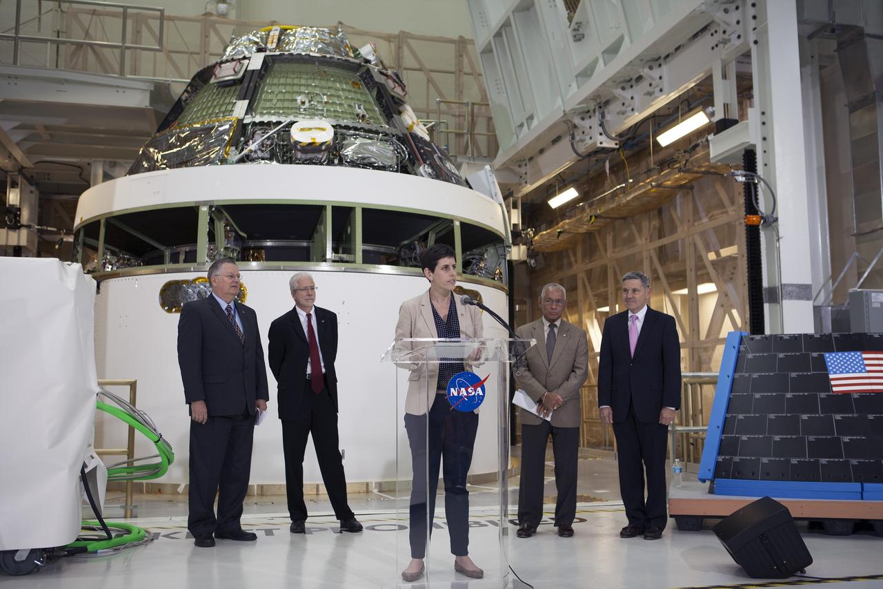 CAPE CANAVERAL, Fla. – NASA Public Affairs Officer Rachel Kraft welcomes members of the media to the Operations and Checkout Building high at NASA's Kennedy Space Center in Florida to mark the T-6 months and counting to the launch of Orion on Exploration Flight Test-1, or EFT-1.  To her right are NASA Administrator Charlie Bolden and Kennedy Director Bob Cabana. To her left are Cleon Lacefield, Lockheed Martin Orion Program manager, and Mark Geyer, NASA Orion Program manager. Behind them is the crew module stacked on the service module in the Final Assembly and System Testing cell. EFT-1 will provide engineers with data about the heat shield's ability to protect Orion and its future crews from the 4,000-degree heat of reentry and an ocean splashdown following the spacecraft’s 20,000-mph reentry from space. Data gathered during the flight will inform decisions about design improvements on the heat shield and other Orion systems, and authenticate existing computer models and new approaches to space systems design and development. This process is critical to reducing overall risks and costs of future Orion missions.    Orion is the exploration spacecraft designed to carry astronauts to destinations not yet explored by humans, including an asteroid and Mars. It will have emergency abort capability, sustain the crew during space travel and provide safe re-entry from deep space return velocities. The first unpiloted test flight of the Orion is scheduled to launch later this year atop a Delta IV rocket from Cape Canaveral Air Force Station in Florida to an altitude of 3,600 miles above the Earth's surface. The two-orbit, four-hour flight test will help engineers evaluate the systems critical to crew safety including the heat shield, parachute system and launch abort system. For more information, visit http://www.nasa.gov/orion. Photo credit: NASA/Kim Shiflett