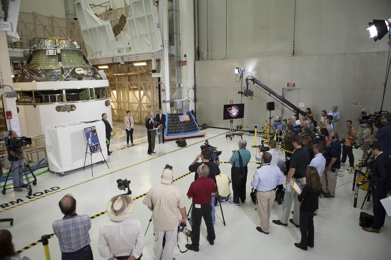 CAPE CANAVERAL, Fla. – Members of the media listen as NASA Orion Program Manager Mark Geyer marks the T-6 months and counting to the launch of Orion on Exploration Flight Test-1, or EFT-1, in the Operations and Checkout Building high bay at NASA's Kennedy Space Center in Florida. To his right is Kennedy Director Bob Cabana. Partially hidden behind him is NASA Administrator Charlie Bolden. To his left is Cleon Lacefield, Lockheed Martin Orion Program manager, and Rachel Kraft, NASA Public Affairs Officer.  Behind them is the crew module stacked on the service module in the Final Assembly and System Testing cell. EFT-1 will provide engineers with data about the heat shield's ability to protect Orion and its future crews from the 4,000-degree heat of reentry and an ocean splashdown following the spacecraft’s 20,000-mph reentry from space. Data gathered during the flight will inform decisions about design improvements on the heat shield and other Orion systems, and authenticate existing computer models and new approaches to space systems design and development. This process is critical to reducing overall risks and costs of future Orion missions.    Orion is the exploration spacecraft designed to carry astronauts to destinations not yet explored by humans, including an asteroid and Mars. It will have emergency abort capability, sustain the crew during space travel and provide safe re-entry from deep space return velocities. The first unpiloted test flight of the Orion is scheduled to launch later this year atop a Delta IV rocket from Cape Canaveral Air Force Station in Florida to an altitude of 3,600 miles above the Earth's surface. The two-orbit, four-hour flight test will help engineers evaluate the systems critical to crew safety including the heat shield, parachute system and launch abort system. For more information, visit http://www.nasa.gov/orion. Photo credit: NASA/Kim Shiflett