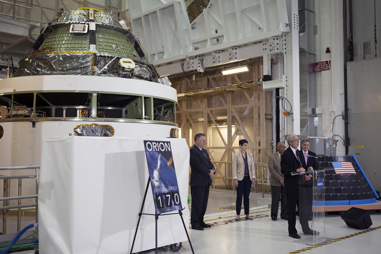 CAPE CANAVERAL, Fla. – Members of the media listen as NASA Orion Program Manager Mark Geyer marks the T-6 months and counting to the launch of Orion on Exploration Flight Test-1, or EFT-1, in the Operations and Checkout Building high bay at NASA's Kennedy Space Center in Florida. To his right is Kennedy Director Bob Cabana. Partially hidden behind him is NASA Administrator Charlie Bolden. To his left is Cleon Lacefield, Lockheed Martin Orion Program manager, and Rachel Kraft, NASA Public Affairs Officer.  Behind them is the crew module stacked on the service module in the Final Assembly and System Testing cell. EFT-1 will provide engineers with data about the heat shield's ability to protect Orion and its future crews from the 4,000-degree heat of reentry and an ocean splashdown following the spacecraft’s 20,000-mph reentry from space. Data gathered during the flight will inform decisions about design improvements on the heat shield and other Orion systems, and authenticate existing computer models and new approaches to space systems design and development. This process is critical to reducing overall risks and costs of future Orion missions.    Orion is the exploration spacecraft designed to carry astronauts to destinations not yet explored by humans, including an asteroid and Mars. It will have emergency abort capability, sustain the crew during space travel and provide safe re-entry from deep space return velocities. The first unpiloted test flight of the Orion is scheduled to launch later this year atop a Delta IV rocket from Cape Canaveral Air Force Station in Florida to an altitude of 3,600 miles above the Earth's surface. The two-orbit, four-hour flight test will help engineers evaluate the systems critical to crew safety including the heat shield, parachute system and launch abort system. For more information, visit http://www.nasa.gov/orion. Photo credit: NASA/Kim Shiflett