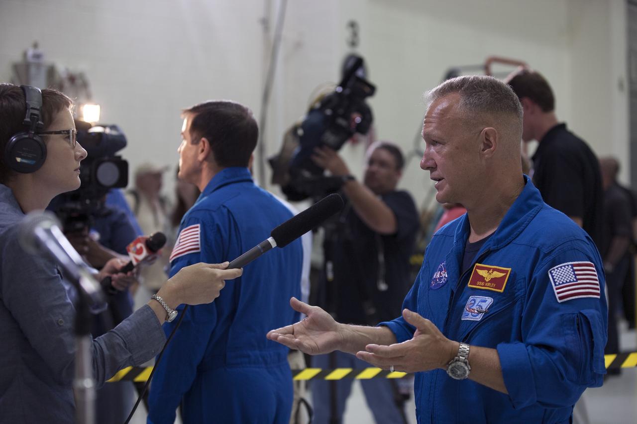 CAPE CANAVERAL, Fla. – NASA astronaut Doug Hurley talks to a member of the media during an event to mark the T-6 months and counting to the launch of Orion on Exploration Flight Test-1, or EFT-1, inside the Operations and Checkout Building high bay at NASA's Kennedy Space Center in Florida. In the background is NASA astronaut Rex Walheim. The crew module has been stacked on the service module in the Final Assembly and System Testing cell. EFT-1 will provide engineers with data about the heat shield's ability to protect Orion and its future crews from the 4,000-degree heat of reentry and an ocean splashdown following the spacecraft’s 20,000-mph reentry from space. Data gathered during the flight will inform decisions about design improvements on the heat shield and other Orion systems, and authenticate existing computer models and new approaches to space systems design and development. This process is critical to reducing overall risks and costs of future Orion missions.    Orion is the exploration spacecraft designed to carry astronauts to destinations not yet explored by humans, including an asteroid and Mars. It will have emergency abort capability, sustain the crew during space travel and provide safe re-entry from deep space return velocities. The first unpiloted test flight of the Orion is scheduled to launch later this year atop a Delta IV rocket from Cape Canaveral Air Force Station in Florida to an altitude of 3,600 miles above the Earth's surface. The two-orbit, four-hour flight test will help engineers evaluate the systems critical to crew safety including the heat shield, parachute system and launch abort system. For more information, visit http://www.nasa.gov/orion. Photo credit: NASA/Kim Shiflett