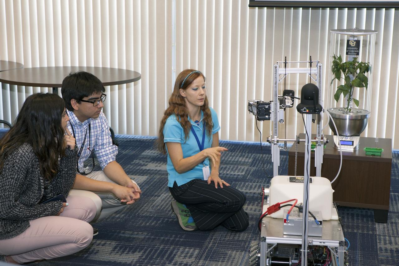 CAPE CANAVERAL, Fla. -- At the Kennedy Space Center in Florida, Heather Hava, who is working on a doctorate in aerospace engineering sciences at the University of Colorado Boulder, describes a Remotely Operated Gardening Rover, or ROGR, which could tend to plants grown in one of the SmartPots, or SPOTS seen on the right. The system is being developed by the graduate students participating in the eXploration HABitat X-Hab Academic Innovation Challenge.      X-Hab Academic Innovation Challenge is a university-level activity designed to engage and retain students in science, technology, engineering and math, or STEM, disciplines. NASA will directly benefit from the effort by sponsoring the development of innovative habitat concepts from universities which may result in innovative ideas and solutions that could be applied to exploration habitats. For more: http://www.nasa.gov/exploration/technology/deep_space_habitat/xhab/ Photo credit: NASA/Daniel Casper