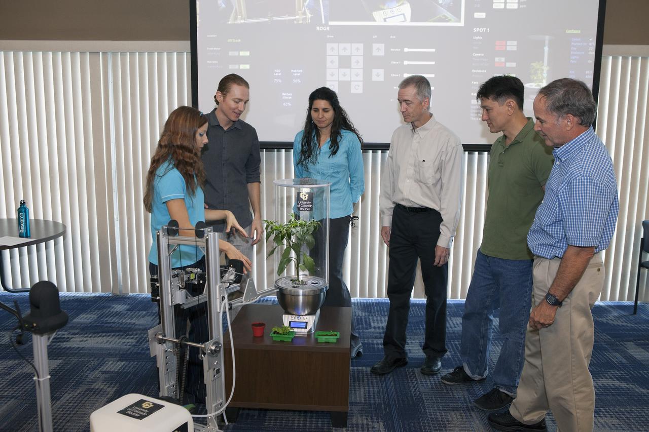 CAPE CANAVERAL, Fla. -- At the Kennedy Space Center in Florida, University of Colorado Boulder graduate students Heather Hava, far left, and Daniel Zukowski, second from the left, describe a computerized SmartPot, or SPOT, which could be used to grow plants in a deep-space habitat. The SPOTs could be tended by a Remotely Operated Gardening Rover, or ROGR, seen on the left. The system is being developed by the graduate students participating in the eXploration HABitat X-Hab Academic Innovation Challenge. From the left are Hava, Zukowski, Gioia Massa of the NASA International Space Station Ground Processing and Research Project Office, Tracy Gill of the NASA Center Planning and Development Directorate, Morgan Simpson of the NASA Ground Processing Directorate, and Ray Wheeler of the NASA Engineering and Technology Directorate.       X-Hab Academic Innovation Challenge is a university-level activity designed to engage and retain students in science, technology, engineering and math, or STEM, disciplines. NASA will directly benefit from the effort by sponsoring the development of innovative habitat concepts from universities which may result in innovative ideas and solutions that could be applied to exploration habitats. For more: http://www.nasa.gov/exploration/technology/deep_space_habitat/xhab/ Photo credit: NASA/Daniel Casper