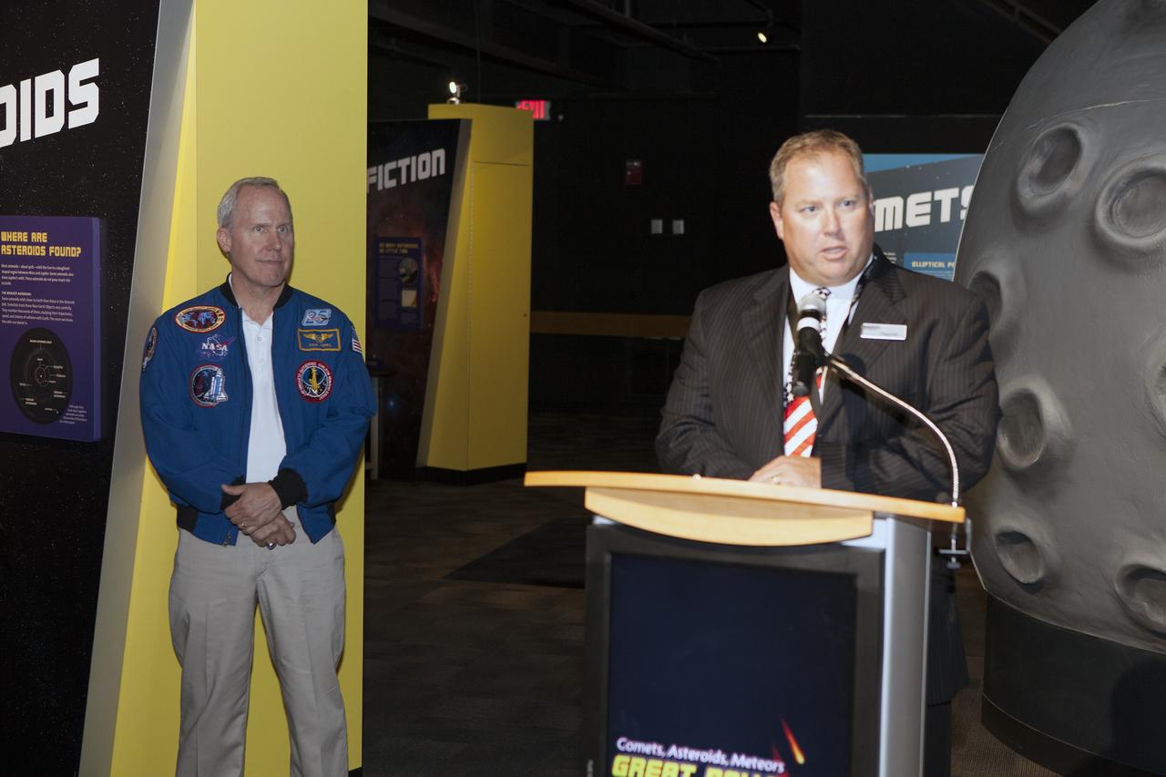 CAPE CANAVERAL, Fla. – Therrin Protze, chief operating officer with Delaware North Parks and Resorts at NASA's Kennedy Space Center Visitor Complex in Florida, welcomes guests to the grand opening of the Great Balls of Fire exhibit. To his left is former NASA astronaut Tom Jones.    Great Balls of Fire shares the story of the origins of our solar system, asteroids and comets and their possible impacts and risks. The 1,500-square-foot exhibit, located in the East Gallery of the IMAX theatre at the visitor complex, features several interactive displays, real meteorites and replica asteroid models. The exhibit is a production of The Space Science Institute's National Center for Interactive Learning. It is a traveling exhibition that also receives funding from NASA and the National Science Foundation. Photo credit: NASA/Daniel Casper