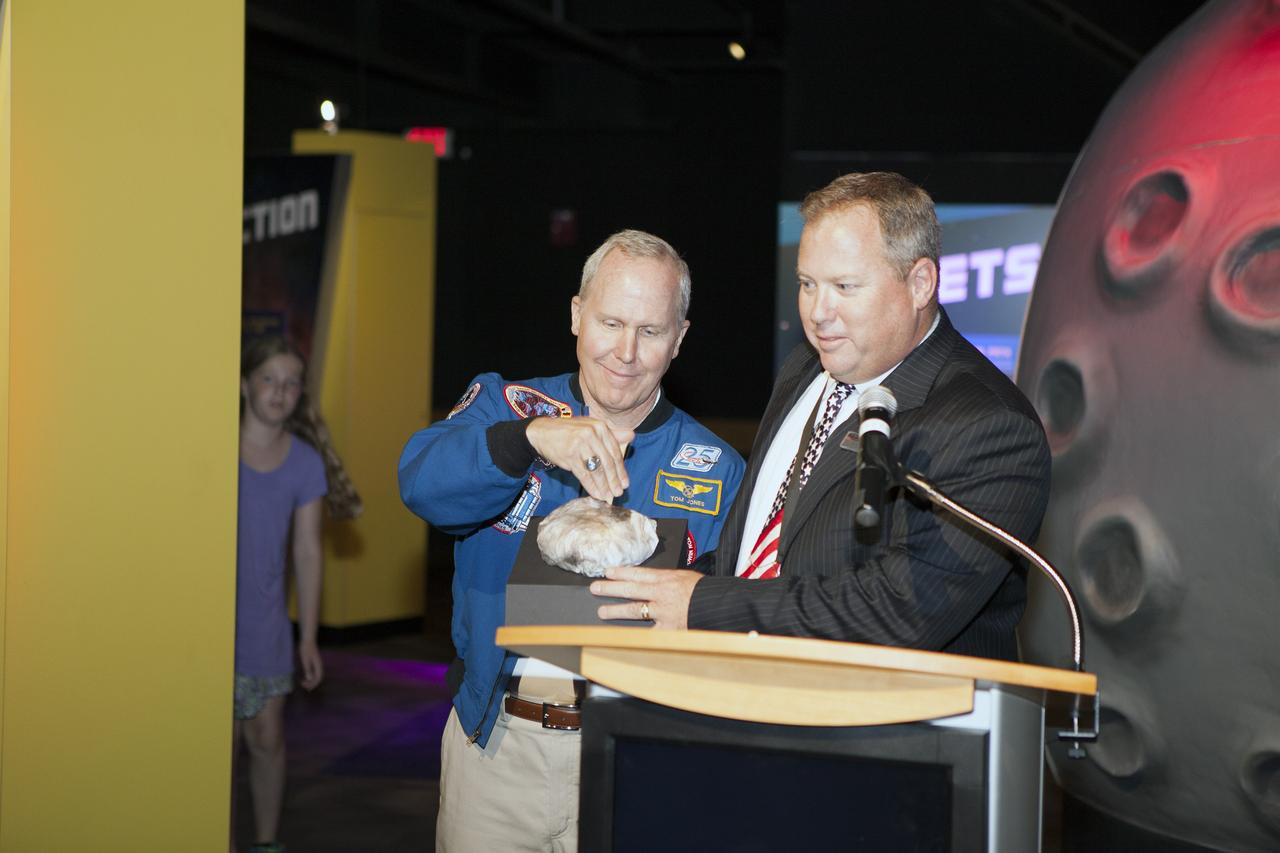 CAPE CANAVERAL, Fla. – Former NASA astronaut Tom Jones, left, presses the button on a simulated model of an asteroid to mark the grand opening of the new Great Balls of Fire exhibit at NASA’s Kennedy Space Center Visitor Complex in Florida. To his right is Therrin Protze, chief operating officer with Delaware North Parks and Resorts at the visitor complex.     Great Balls of Fire shares the story of the origins of our solar system, asteroids and comets and their possible impacts and risks. The 1,500-square-foot exhibit, located in the East Gallery of the IMAX theatre at the visitor complex, features several interactive displays, real meteorites and replica asteroid models. The exhibit is a production of The Space Science Institute's National Center for Interactive Learning. It is a traveling exhibition that also receives funding from NASA and the National Science Foundation. Photo credit: NASA/Daniel Casper