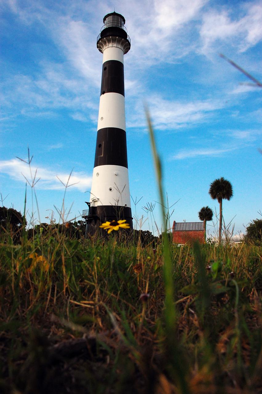 CAPE CANAVERAL, Fla. -- Natural vegetation surrounds the historic Cape Canaveral Light on Cape Canaveral Air Force Station in Florida. The low structure to the right of the lighthouse is the original oil house. The U.S. Air Force now owns the lighthouse. The first lighthouse on Cape Canaveral was built near the tip of the Cape in 1848. The structure was only about 60 feet high with a rather dim light powered by whale oil. In 1859, work began nearby on a new, taller iron structure. Construction was halted during the Civil War, and the lighthouse was not finished until 1868. The structure, with a brick lining inside its iron exterior, was painted with its "daymark" black and white horizontal bands in 1873 to make it easier to identify during the day as a navigation point. Between 1892 and 1894, the lighthouse was dismantled and moved to a new location about a mile from the coast, where it stands today. For more information on the lighthouse, visit http://www.nasa.gov/centers/kennedy/about/history/lighthouse.html. Photo credit: NASA/Ben Smegelsky