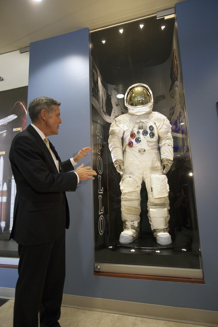 KSC-2014-3220 – CAPE CANAVERAL, Fla. -- At the Kennedy Space Center in Florida, Center Director Robert Cabana unveils an Apollo-era spacesuit on display in the lobby of the newly named Neil Armstrong Operations and Checkout Building. The facility has been renamed for Apollo 11 astronaut Neil Armstrong, the first person to set foot on the moon. The building's high bay is being used to support the agency's new Orion spacecraft and is the same spaceport facility where the Apollo 11 command/service module and lunar module were prepped for the first lunar landing mission in 1969. Orion is designed to take humans farther than they’ve ever gone before, serving as the exploration vehicle that will carry astronauts to deep space and sustain the crew during travel to destinations such as an asteroid or Mars.    The unveiling was part of NASA's 45th anniversary celebration of the Apollo 11 moon landing. As the world watched, Apollo 11 astronauts landed in the moon's Sea of Tranquility aboard the lunar module, Eagle, on July 20, 1969, as the command module, Columbia, orbited overhead. For more: http://www.nasa.gov/press/2014/july/nasa-honors-historic-first-moon-landing-eyes-first-mars-mission/ Photo credit: NASA/Kim Shiflett