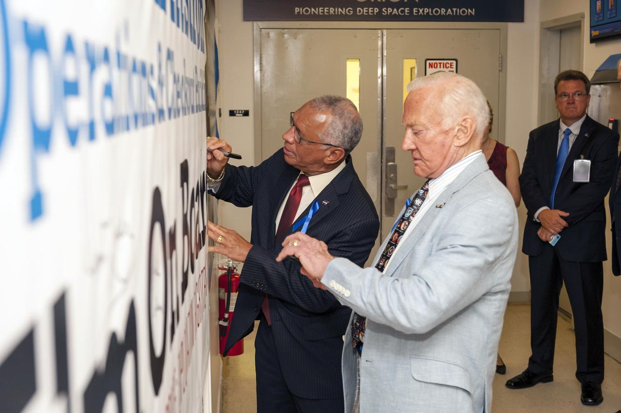 CAPE CANAVERAL, Fla. -- At NASA's Kennedy Space Center in Florida, NASA Administrator Charles Bolden, left, signs a banner displaying the new name of the Operations and Checkout Building, as Apollo 11 moonwalker Buzz Aldrin prepares to sign. The banner signing followed a ceremony renaming the refurbished Operations and Checkout Building for Apollo 11 astronaut Neil Armstrong, the first person to set foot on the moon. The building's high bay is being used to support the agency's new Orion spacecraft and is the same spaceport facility where the Apollo 11 command/service module and lunar module were prepped for the first lunar landing mission in 1969. Orion is designed to take humans farther than they’ve ever gone before, serving as the exploration vehicle that will carry astronauts to deep space and sustain the crew during travel to destinations such as an asteroid or Mars. The ceremony was part of NASA's 45th anniversary celebration of the Apollo 11 moon landing. As the world watched, Neil Armstrong and Buzz Aldrin landed in the moon's Sea of Tranquility on July 20, 1969, aboard the lunar module Eagle. Meanwhile, crewmate Michael Collins orbited above in the command module Columbia. For more, visit http://www.nasa.gov/press/2014/july/nasa-honors-historic-first-moon-landing-eyes-first-mars-mission. Photo credit: NASA/Kevin O'Connell