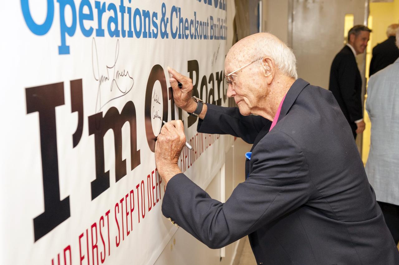 CAPE CANAVERAL, Fla. -- Apollo 11 command module pilot Michael Collins signs a banner displaying the new name of the Operations and Checkout Building at NASA's Kennedy Space Center in Florida. The banner signing followed a ceremony renaming the refurbished building for Apollo 11 astronaut Neil Armstrong, the first person to set foot on the moon. The building's high bay is being used to support the agency's new Orion spacecraft and is the same spaceport facility where the Apollo 11 command/service module and lunar module were prepped for the first lunar landing mission in 1969. Orion is designed to take humans farther than they’ve ever gone before, serving as the exploration vehicle that will carry astronauts to deep space and sustain the crew during travel to destinations such as an asteroid or Mars.    The ceremony was part of NASA's 45th anniversary celebration of the Apollo 11 moon landing. As the world watched, Neil Armstrong and Buzz Aldrin landed in the moon's Sea of Tranquility on July 20, 1969, aboard the lunar module Eagle. Meanwhile, crewmate Michael Collins orbited above in the command module Columbia. For more, visit http://www.nasa.gov/press/2014/july/nasa-honors-historic-first-moon-landing-eyes-first-mars-mission. Photo credit: NASA/Kevin O'Connell