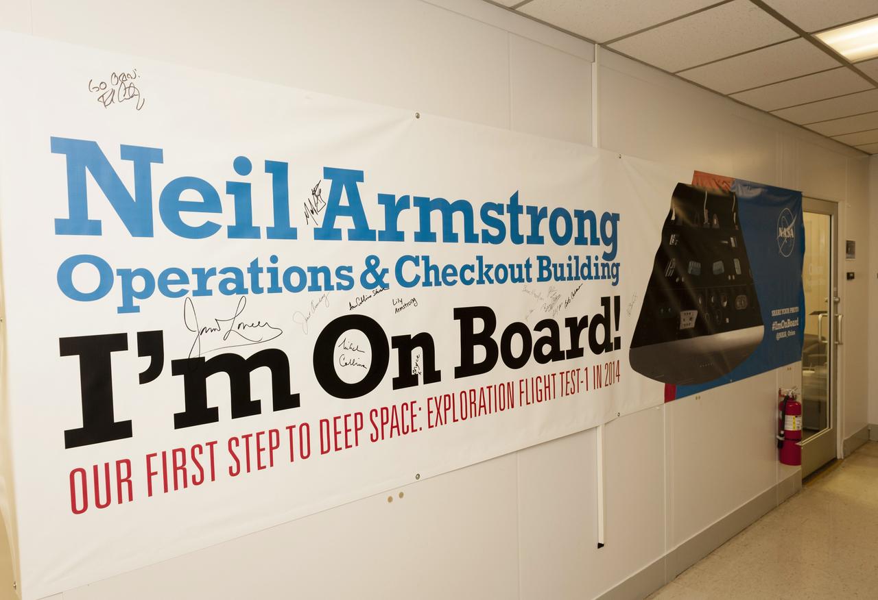 CAPE CANAVERAL, Fla. -- A banner displaying the new name of the Operations and Checkout Building at NASA's Kennedy Space Center in Florida is signed by Apollo astronauts and their families. The banner signing followed a ceremony renaming the refurbished building for Apollo 11 astronaut Neil Armstrong, the first person to set foot on the moon. The building's high bay is being used to support the agency's new Orion spacecraft and is the same spaceport facility where the Apollo 11 command/service module and lunar module were prepped for the first lunar landing mission in 1969. The Orion spacecraft is designed to take humans farther than they’ve ever gone before, serving as the exploration vehicle that will carry astronauts to deep space and sustain the crew during travel to destinations such as an asteroid or Mars. Orion's first flight will be Exploration Fight Test-1, planned for December 2014. The ceremony was part of NASA's 45th anniversary celebration of the Apollo 11 moon landing. As the world watched, Neil Armstrong and Buzz Aldrin landed in the moon's Sea of Tranquility on July 20, 1969, aboard the lunar module Eagle. Meanwhile, crewmate Michael Collins orbited above in the command module Columbia. For more, visit http://www.nasa.gov/press/2014/july/nasa-honors-historic-first-moon-landing-eyes-first-mars-mission. Photo credit: NASA/Kevin O'Connell