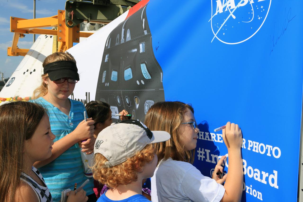 SAN DIEGO, Calif. – At the U.S. Naval Base San Diego in California, children sign a banner near the Orion boilerplate test vehicle during an outreach event at the naval base. The USS Anchorage is being prepared for the Orion Underway Recovery Test 2. The test vehicle and other hardware will be loaded into the well deck of the ship and head out to sea in the Pacific Ocean off the coast of San Diego. NASA, Lockheed Martin and the U.S. Navy will conduct the test to prepare for recovery of the Orion crew module, forward bay cover and parachutes on its return from a deep space mission. The underway recovery test will allow the teams to demonstrate and evaluate the recovery processes, procedures, new support hardware and personnel in open waters. The Ground Systems Development and Operations Program will conduct the underway recovery tests. Orion is the exploration spacecraft designed to carry astronauts to destinations not yet explored by humans, including an asteroid and Mars. It will have emergency abort capability, sustain the crew during space travel and provide safe re-entry from deep space return velocities. The first unpiloted test flight of the Orion is scheduled to launch in 2014 atop a Delta IV rocket and in 2017 on NASA’s Space Launch System rocket. For more information, visit http://www.nasa.gov/orion. Photo credit: NASA/Kim Shiflett