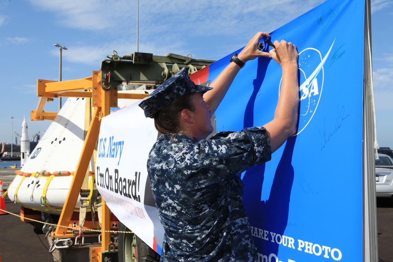 SAN DIEGO, Calif. – At the U.S. Naval Base San Diego in California, former NASA astronaut Heidi Piper signs the banner near the Orion boilerplate test vehicle during an outreach event at the naval base. The USS Anchorage is being prepared for the Orion Underway Recovery Test 2. The test vehicle and other hardware will be loaded into the well deck of the ship and head out to sea in the Pacific Ocean off the coast of San Diego. NASA, Lockheed Martin and the U.S. Navy will conduct the test to prepare for recovery of the Orion crew module, forward bay cover and parachutes on its return from a deep space mission. The underway recovery test will allow the teams to demonstrate and evaluate the recovery processes, procedures, new support hardware and personnel in open waters. The Ground Systems Development and Operations Program will conduct the underway recovery tests. Orion is the exploration spacecraft designed to carry astronauts to destinations not yet explored by humans, including an asteroid and Mars. It will have emergency abort capability, sustain the crew during space travel and provide safe re-entry from deep space return velocities. The first unpiloted test flight of the Orion is scheduled to launch in 2014 atop a Delta IV rocket and in 2017 on NASA’s Space Launch System rocket. For more information, visit http://www.nasa.gov/orion. Photo credit: NASA/Kim Shiflett