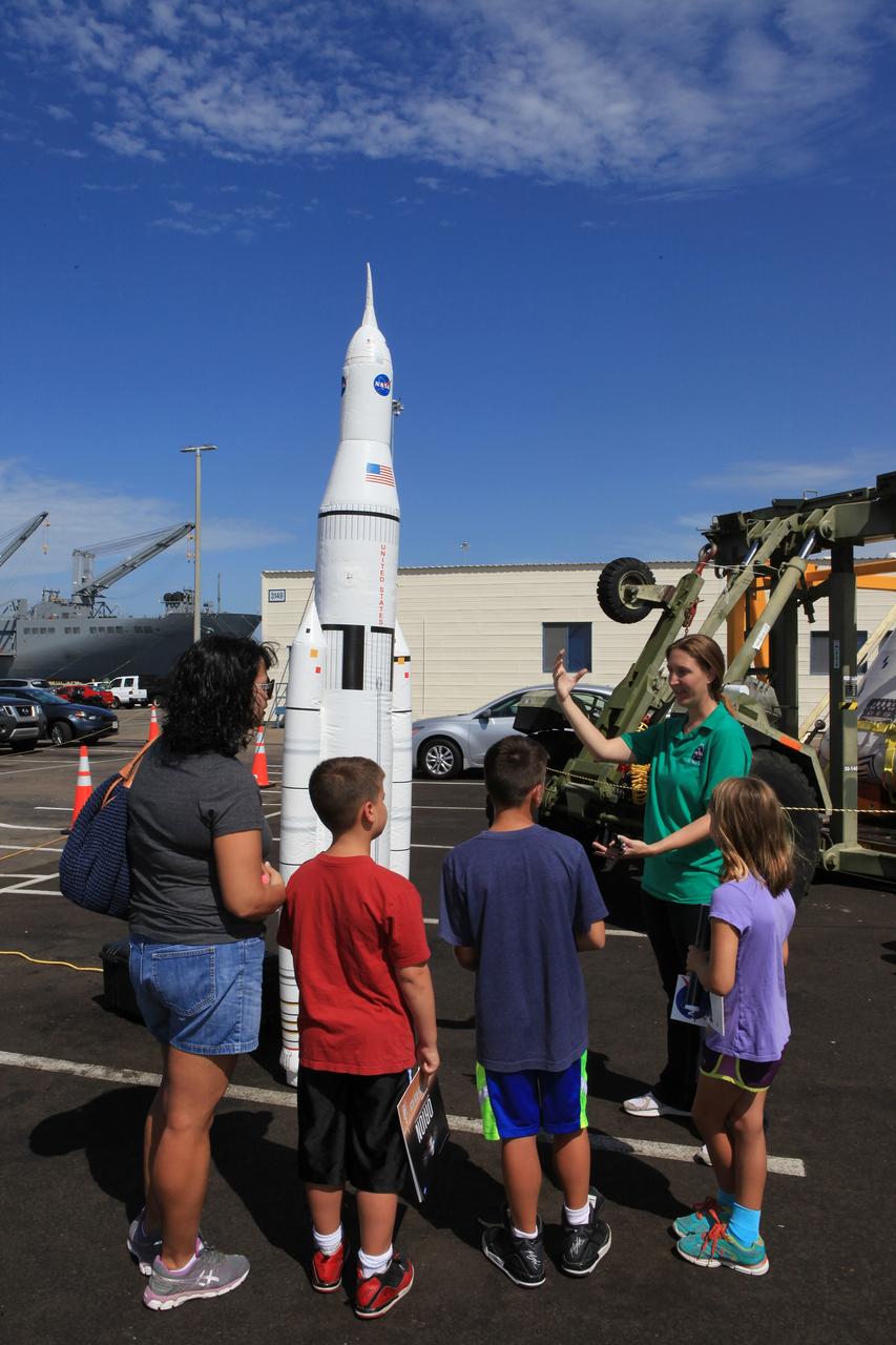 SAN DIEGO, Calif. – At the U.S. Naval Base San Diego in California, NASA Public Affairs Officer Amber Philman describes the Space Launch System and Orion spacecraft to visitors during an outreach event at the naval base. The USS Anchorage is being prepared for the Orion Underway Recovery Test 2. The Orion boilerplate test vehicle and other hardware will be loaded into the well deck of the ship and head out to sea in the Pacific Ocean off the coast of San Diego. NASA, Lockheed Martin and the U.S. Navy will conduct the test to prepare for recovery of the Orion crew module, forward bay cover and parachutes on its return from a deep space mission. The underway recovery test will allow the teams to demonstrate and evaluate the recovery processes, procedures, new support hardware and personnel in open waters. The Ground Systems Development and Operations Program will conduct the underway recovery tests. Orion is the exploration spacecraft designed to carry astronauts to destinations not yet explored by humans, including an asteroid and Mars. It will have emergency abort capability, sustain the crew during space travel and provide safe re-entry from deep space return velocities. The first unpiloted test flight of the Orion is scheduled to launch in 2014 atop a Delta IV rocket and in 2017 on NASA’s Space Launch System rocket. For more information, visit http://www.nasa.gov/orion. Photo credit: NASA/Kim Shiflett