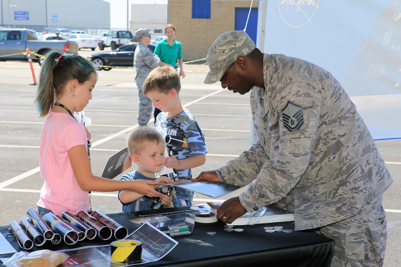 SAN DIEGO, Calif. – At the U.S. Naval Base San Diego in California, children pick up Orion posters from U.S. Navy personnel during an outreach event at the naval base. The Orion boilerplate test vehicle is on display. The USS Anchorage is being prepared for the Orion Underway Recovery Test 2. The test vehicle and other hardware will be loaded into the well deck of the ship and head out to sea in the Pacific Ocean off the coast of San Diego. NASA, Lockheed Martin and the U.S. Navy will conduct the test to prepare for recovery of the Orion crew module, forward bay cover and parachutes on its return from a deep space mission. The underway recovery test will allow the teams to demonstrate and evaluate the recovery processes, procedures, new support hardware and personnel in open waters. The Ground Systems Development and Operations Program will conduct the underway recovery tests. Orion is the exploration spacecraft designed to carry astronauts to destinations not yet explored by humans, including an asteroid and Mars. It will have emergency abort capability, sustain the crew during space travel and provide safe re-entry from deep space return velocities. The first unpiloted test flight of the Orion is scheduled to launch in 2014 atop a Delta IV rocket and in 2017 on NASA’s Space Launch System rocket. For more information, visit http://www.nasa.gov/orion. Photo credit: NASA/Kim Shiflett