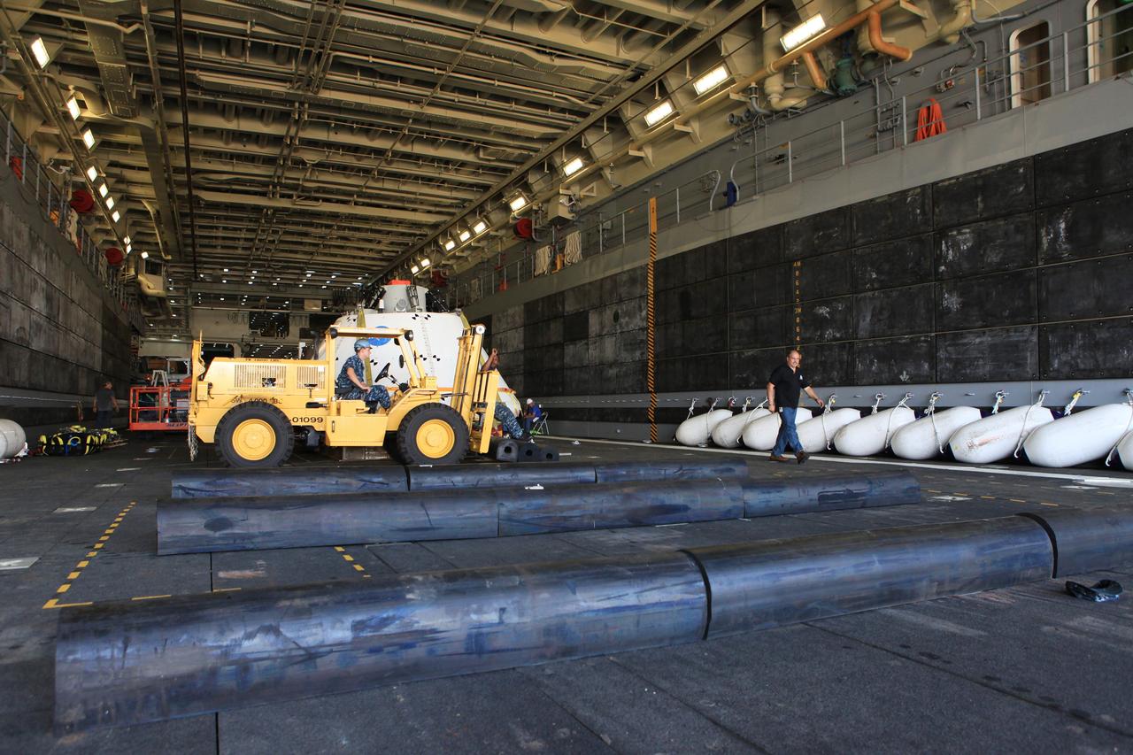 SAN DIEGO, Calif. – At the U.S. Naval Base San Diego in California, the Orion boilerplate test vehicle and cradle have been positioned in the well deck of the USS Anchorage in preparation for Underway Recovery Test 2. A worker moves a piece of the handling fixture that was removed from around the test vehicle. NASA, Lockheed Martin and the U.S. Navy will conduct tests in the Pacific Ocean to prepare for recovery of the Orion crew module on its return from a deep space mission. The second underway recovery test will allow the teams to demonstrate and evaluate the recovery processes, procedures, new hardware and personnel in open waters.     The Ground Systems Development and Operations Program is conducting the underway recovery tests. Orion is the exploration spacecraft designed to carry astronauts to destinations not yet explored by humans, including an asteroid and Mars. It will have emergency abort capability, sustain the crew during space travel and provide safe re-entry from deep space return velocities. The first unpiloted test flight of the Orion is scheduled to launch in 2014 atop a Delta IV rocket and in 2017 on NASA’s Space Launch System rocket. For more information, visit http://www.nasa.gov/orion. Photo credit: NASA/Kim Shiflett