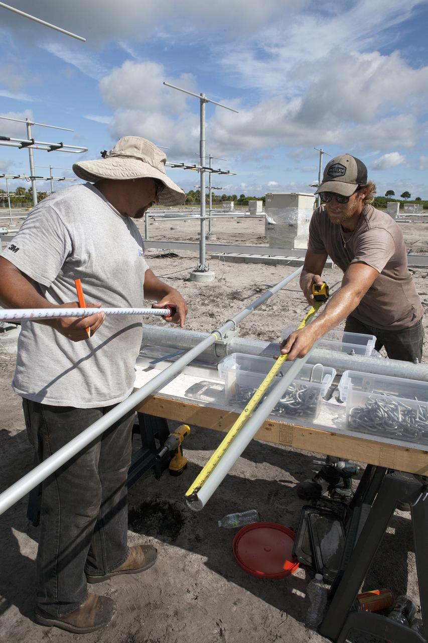 CAPE CANAVERAL, Fla. – Felix Gamez and Jacob Walls, right, of Qinetiq North America take measurements as they prepare to install an antenna in the antenna field for NASA Kennedy Space Center’s Doppler radar wind profiler.     Located near the spaceport’s Shuttle Landing Facility runway, the profiler is being upgraded to a new, state-of-the-art version that will help forecasters and launch teams characterize upper-level winds in the area. This profiler will help in the detection of wind-shear conditions during launch. Photo credit: NASA/Ben Smegelsky