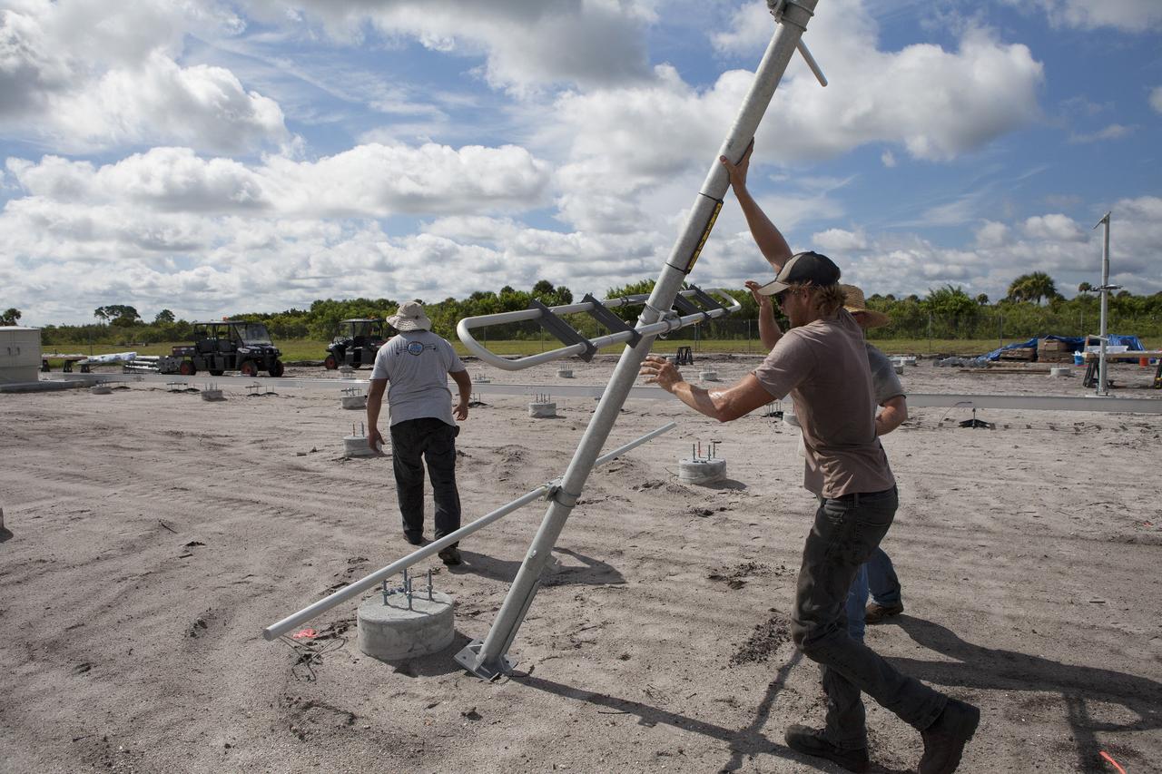 CAPE CANAVERAL, Fla. – Jacob Walls, right, and Robert Novak of Qinetiq North America raise a new antenna in position prior to its installation in the antenna field for NASA Kennedy Space Center’s Doppler radar wind profiler.    Located near the spaceport’s Shuttle Landing Facility runway, the profiler is being upgraded to a new, state-of-the-art version that will help forecasters and launch teams characterize upper-level winds in the area. This profiler will help in the detection of wind-shear conditions during launch. Photo credit: NASA/Ben Smegelsky