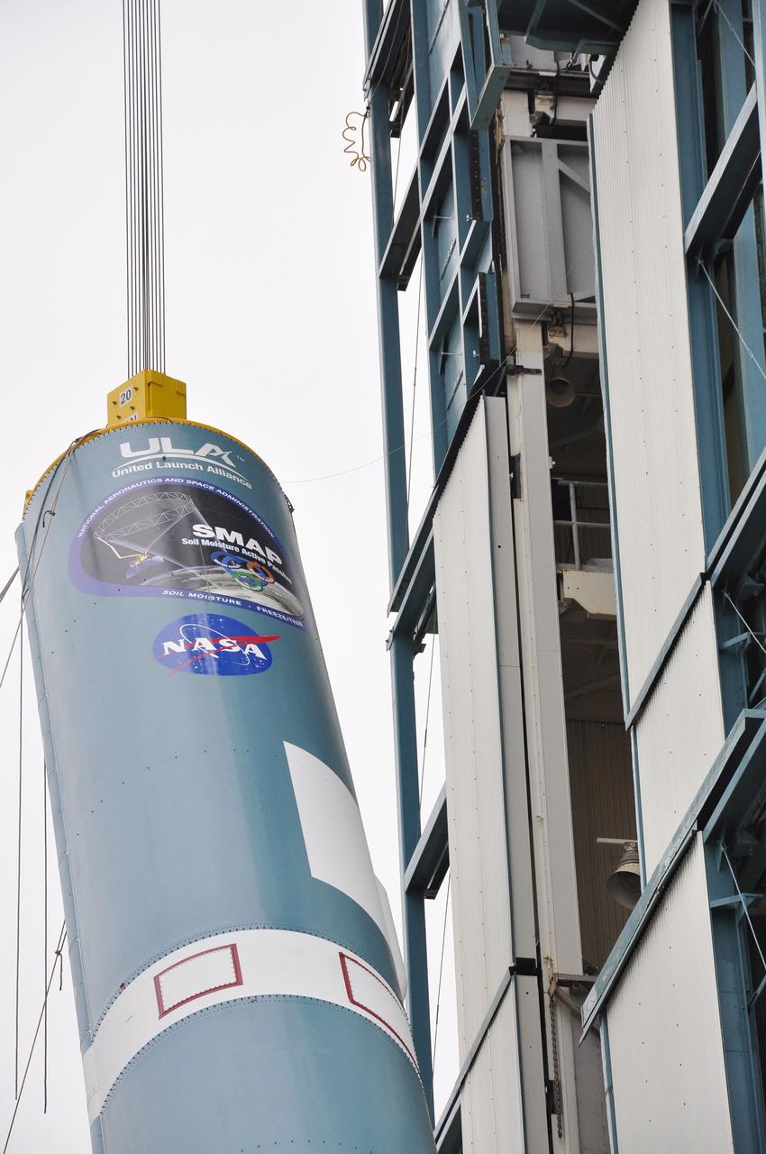 VANDENBERG AIR FORCE BASE, Calif. – A crane hoists the first stage of the United Launch Alliance Delta II rocket for NASA's Soil Moisture Active Passive mission, or SMAP, into a vertical position beside the mobile service tower at Space Launch Complex 2 on Vandenberg Air Force Base in California.    SMAP will provide global measurements of soil moisture and its freeze/thaw state. These measurements will be used to enhance understanding of processes that link the water, energy and carbon cycles, and to extend the capabilities of weather and climate prediction models. SMAP data also will be used to quantify net carbon flux in boreal landscapes and to develop improved flood prediction and drought monitoring capabilities. Launch is scheduled for November 2014. To learn more about SMAP, visit http://smap.jpl.nasa.gov.  Photo credit: NASA/Randy Beaudoin