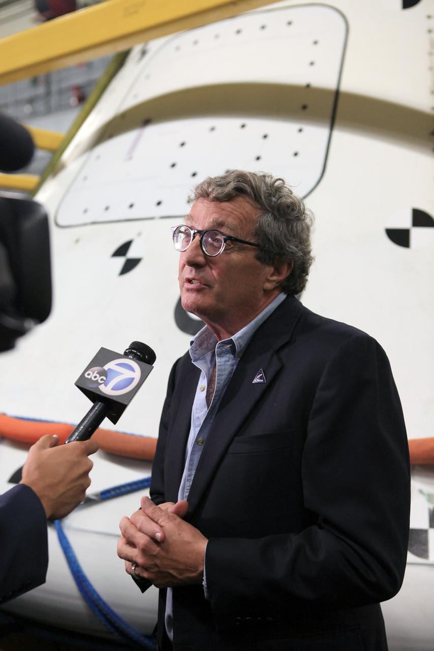 LOS ANGELES, Calif. – Larry Price, Lockheed Martin Space Systems deputy program manager for Orion, talks with a reporter in the well deck of the USS Anchorage after completion of Underway Recovery Test 2. Behind him is the Orion boilerplate test vehicle secured in its recovery cradle. NASA, Lockheed Martin and the U.S. Navy completed the recovery test in the Pacific Ocean off the coast of San Diego to prepare for recovery of the Orion crew module on its return from a deep space mission. The underway recovery test allowed the teams to demonstrate and evaluate the recovery processes, procedures, new hardware and personnel in open waters. The U.S. Navy ship is in Los Angeles for LA Navy Days. The Ground Systems Development and Operations Program conducted the underway recovery test. Orion is the exploration spacecraft designed to carry astronauts to destinations not yet explored by humans, including an asteroid and Mars. It will have emergency abort capability, sustain the crew during space travel and provide safe re-entry from deep space return velocities. The first unpiloted test flight of the Orion is scheduled to launch in 2014 atop a Delta IV rocket and in 2017 on NASA’s Space Launch System rocket. For more information, visit http://www.nasa.gov/orion. Photo credit: Kim Shiflett