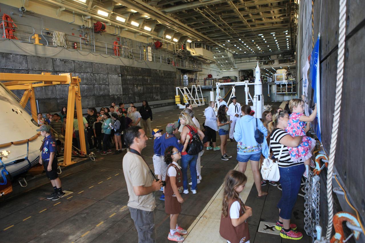 LOS ANGELES, Calif. – Visitors tour the well deck of the USS Anchorage and view the Orion boilerplate test vehicle secured in its recovery cradle and other support hardware during the Science, Technology, Engineering and Mathematics, or STEM, Expo for L.A. Navy Days at the Port of Los Angeles in California. At right, visitors sign an Orion banner. Behind them is a mock-up of NASA’s Space Launch System and Orion spacecraft. NASA, Lockheed Martin and the U.S. Navy completed Underway Recovery Test 2 on the Orion test vehicle in the Pacific Ocean off the coast of San Diego to prepare for recovery of the Orion crew module on its return from a deep space mission. The underway recovery test allowed the teams to demonstrate and evaluate the recovery processes, procedures, new hardware and personnel in open waters.    The Ground Systems Development and Operations Program conducted the underway recovery test. Orion is the exploration spacecraft designed to carry astronauts to destinations not yet explored by humans, including an asteroid and Mars. It will have emergency abort capability, sustain the crew during space travel and provide safe re-entry from deep space return velocities. The first unpiloted test flight of the Orion is scheduled to launch in 2014 on Exploration Flight Test-1, or EFT-1, atop a Delta IV rocket and in 2017 on NASA’s Space Launch System rocket. For more information, visit http://www.nasa.gov/orion. Photo credit: Kim Shiflett