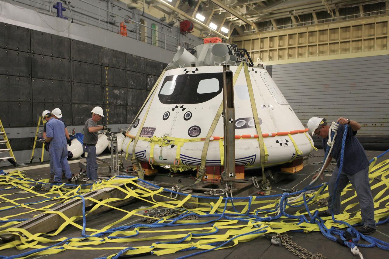 SAN DIEGO, Calif. – The Orion boilerplate test vehicle is secured on its cradle in the well deck of the U.S. Navy's USS Anchorage in preparation for Underway Recovery Test 2 in the Pacific Ocean off the coast of San Diego. Workers are installing a safety barrier near the test vehicle to keep it from going further into the well deck as it fills with water. NASA, Lockheed Martin and the U.S. Navy will conduct the test to prepare for recovery of the Orion crew module on its return from a deep space mission. The underway recovery test will allow the team to demonstrate and evaluate the recovery processes, procedures, new hardware and personnel in open waters.    The Ground Systems Development and Operations Program is conducting the underway recovery test. Orion is the exploration spacecraft designed to carry astronauts to destinations not yet explored by humans, including an asteroid and Mars. It will have emergency abort capability, sustain the crew during space travel and provide safe re-entry from deep space return velocities. The first unpiloted test flight of the Orion is scheduled to launch in 2014 atop a Delta IV rocket and in 2017 on NASA’s Space Launch System rocket. For more information, visit http://www.nasa.gov/orion. Photo credit: NASA/Kim Shiflett