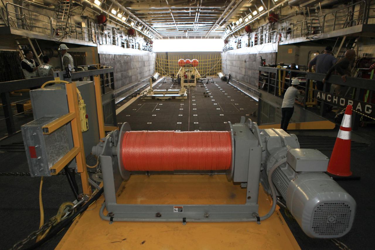SAN DIEGO, Calif. – Inside the well deck of the U.S. Navy's USS Anchorage, the Orion boilerplate test vehicle is secured on its cradle before the start of a portion of Underway Recovery Test 2. A winch line leads to the test vehicle and tether lines have been attached to control Orion. The bright orange stabilizers have been readied to keep Orion upright in the water if needed. NASA, Lockheed Martin and the U.S. Navy are conducting the test in the Pacific Ocean off the coast of San Diego to prepare for recovery of the Orion crew module on its return from a deep space mission. The underway recovery test will allow the team to demonstrate and evaluate the recovery processes, procedures, new hardware and personnel in open waters.    The Ground Systems Development and Operations Program is conducting the underway recovery test. Orion is the exploration spacecraft designed to carry astronauts to destinations not yet explored by humans, including an asteroid and Mars. It will have emergency abort capability, sustain the crew during space travel and provide safe re-entry from deep space return velocities. The first unpiloted test flight of the Orion is scheduled to launch in 2014 atop a Delta IV rocket and in 2017 on NASA’s Space Launch System rocket. For more information, visit http://www.nasa.gov/orion. Photo credit: NASA/Kim Shiflett