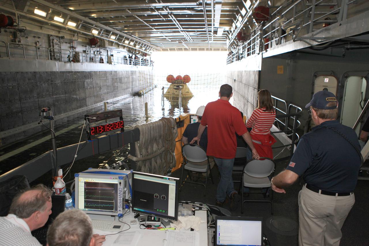 SAN DIEGO, Calif. – Inside the U.S. Navy’s USS Anchorage, NASA, Lockheed Martin and U.S. Navy personnel watch as the well deck fills with water around the Orion boilerplate test vehicle in preparation for a portion of Underway Recovery Test 2 in the Pacific Ocean off the coast of San Diego. Tether lines are attached to the test vehicle to control it and a safety barrier has been installed to prevent Orion from going further into the well deck. The test will help the team prepare for recovery of the Orion crew module on its return from a deep space mission. The underway recovery test will allow the team to demonstrate and evaluate the recovery processes, procedures, new hardware and personnel in open waters.    The Ground Systems Development and Operations Program is conducting the underway recovery test. Orion is the exploration spacecraft designed to carry astronauts to destinations not yet explored by humans, including an asteroid and Mars. It will have emergency abort capability, sustain the crew during space travel and provide safe re-entry from deep space return velocities. The first unpiloted test flight of the Orion is scheduled to launch in 2014 atop a Delta IV rocket and in 2017 on NASA’s Space Launch System rocket. For more information, visit http://www.nasa.gov/orion. Photo credit: NASA/Kim Shiflett
