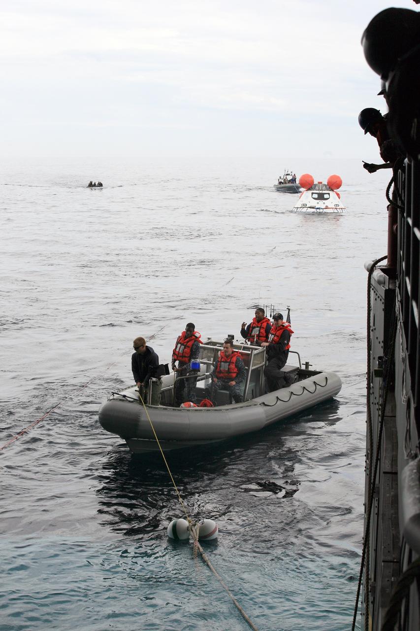 SAN DIEGO, Calif. – U.S. Navy personnel in a rigid hull inflatable boat use tether lines to bring the Orion boilerplate test vehicle back to the USS Anchorage during a portion of Underway Recovery Test 2 in the Pacific Ocean off the coast of San Diego. Behind the test vehicle is another rigid hull inflatable boat. To the far left are U.S. Navy divers in a Zodiac boat. NASA, Lockheed Martin and the U.S. Navy are conducting the test to prepare for recovery of the Orion crew module on its return from a deep space mission. The underway recovery test will allow the team to demonstrate and evaluate the recovery processes, procedures, new hardware and personnel in open waters.    The Ground Systems Development and Operations Program is conducting the underway recovery test. Orion is the exploration spacecraft designed to carry astronauts to destinations not yet explored by humans, including an asteroid and Mars. It will have emergency abort capability, sustain the crew during space travel and provide safe re-entry from deep space return velocities. The first unpiloted test flight of the Orion is scheduled to launch in 2014 atop a Delta IV rocket and in 2017 on NASA’s Space Launch System rocket. For more information, visit http://www.nasa.gov/orion. Photo credit: NASA/Kim Shiflett