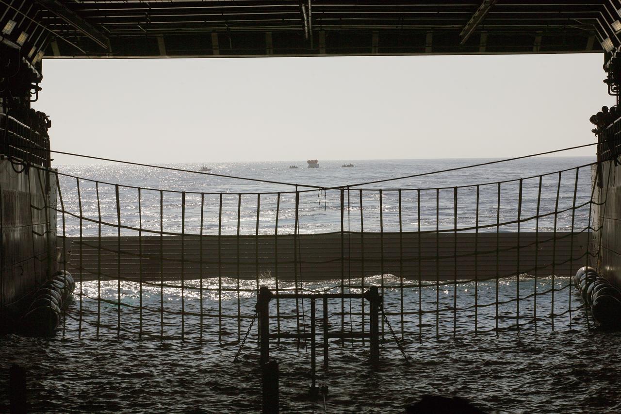 SAN DIEGO, Calif. – A view from inside the well deck of the U.S. Navy’s USS Anchorage, the Orion boilerplate test vehicle floats in the Pacific Ocean off the coast of San Diego during a portion of the Underway Recovery Test 2. Nearby, U.S. Navy personnel in a rigid hull inflatable boat practice capturing the test vehicle with tether lines.    The testing is being conducted to prepare for recovery of the Orion crew module on its return from a deep-space mission. The underway recovery test will allow the team to demonstrate and evaluate the recovery processes, procedures, new hardware and personnel in open waters. The Ground Systems Development and Operations Program is conducting the underway recovery test. Orion is the exploration spacecraft designed to carry astronauts to destinations not yet explored by humans, including an asteroid and Mars. It will have emergency abort capability, sustain the crew during space travel and provide safe re-entry from deep-space return velocities. The first unpiloted test flight of the Orion is scheduled to launch in 2014 atop a Delta IV rocket and in 2017 on NASA’s Space Launch System rocket. For more information, visit http://www.nasa.gov/orion. Photo credit: NASA/Kim Shiflett