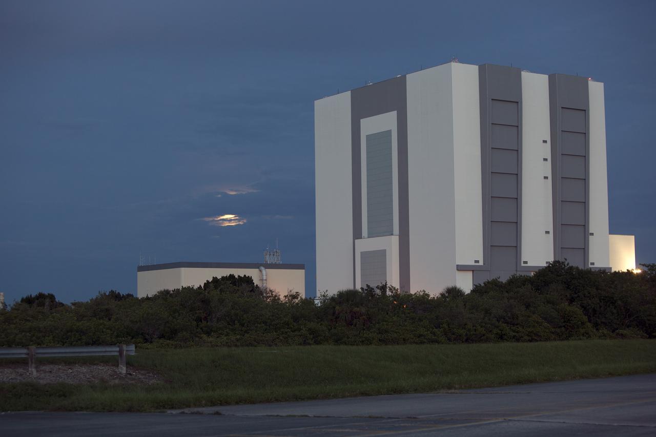 CAPE CANAVERAL, Fla. – A “supermoon” begins to rise through the clouds near the 525-foot-tall Vehicle Assembly Building in Launch Complex 39 at NASA’s Kennedy Space Center in Florida.    The scientific term for the supermoon phenomenon is "perigee moon." Full moons vary in size because of the oval shape of the moon's orbit. The moon follows an elliptical path around Earth with one side about 50,000 kilometers closer than the other. Full moons that occur on the perigee side of the moon's orbit seem extra big and bright. For additional information, visit http://science.nasa.gov/science-news/science-at-nasa/2014/10jul_supermoons/. Photo credit: NASA/Ben Smegelsky